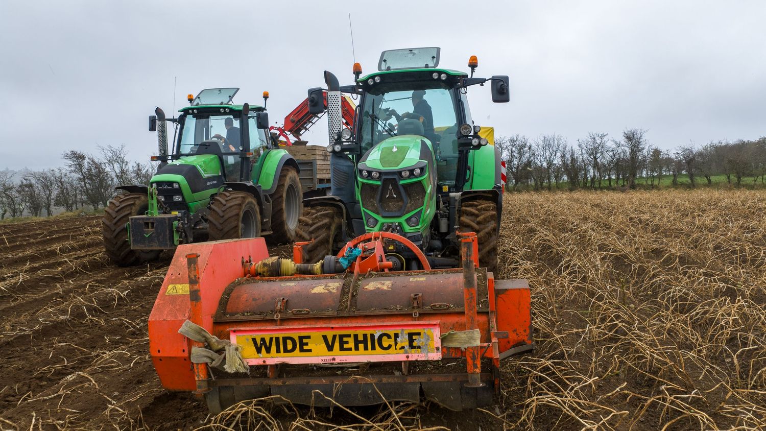 Agricultural machinery and tractors working in fields to prepare soil and harvest crops during farming operations.