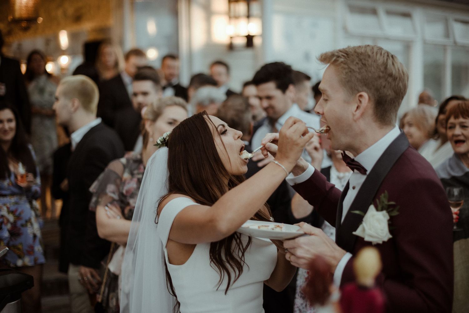Joyful wedding celebration moment as couple shares cake during reception at Villa Malla in Filtvet, one of the greatest venues in Norway.