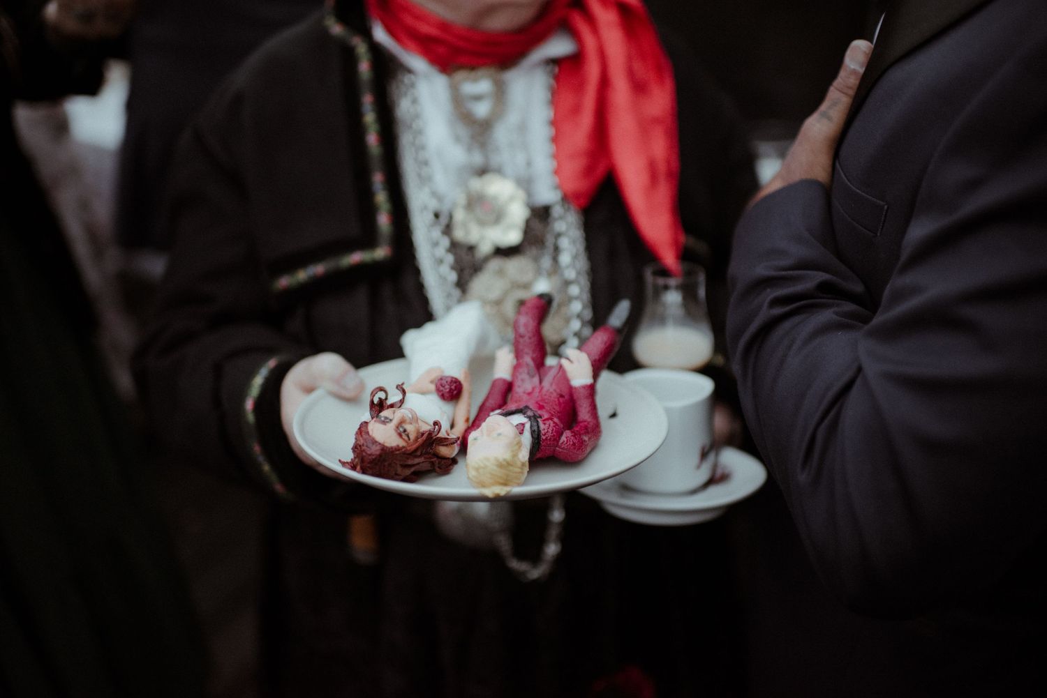 Someone holding a tray with white desserts and red garnishes at what appears to be a catered event.
