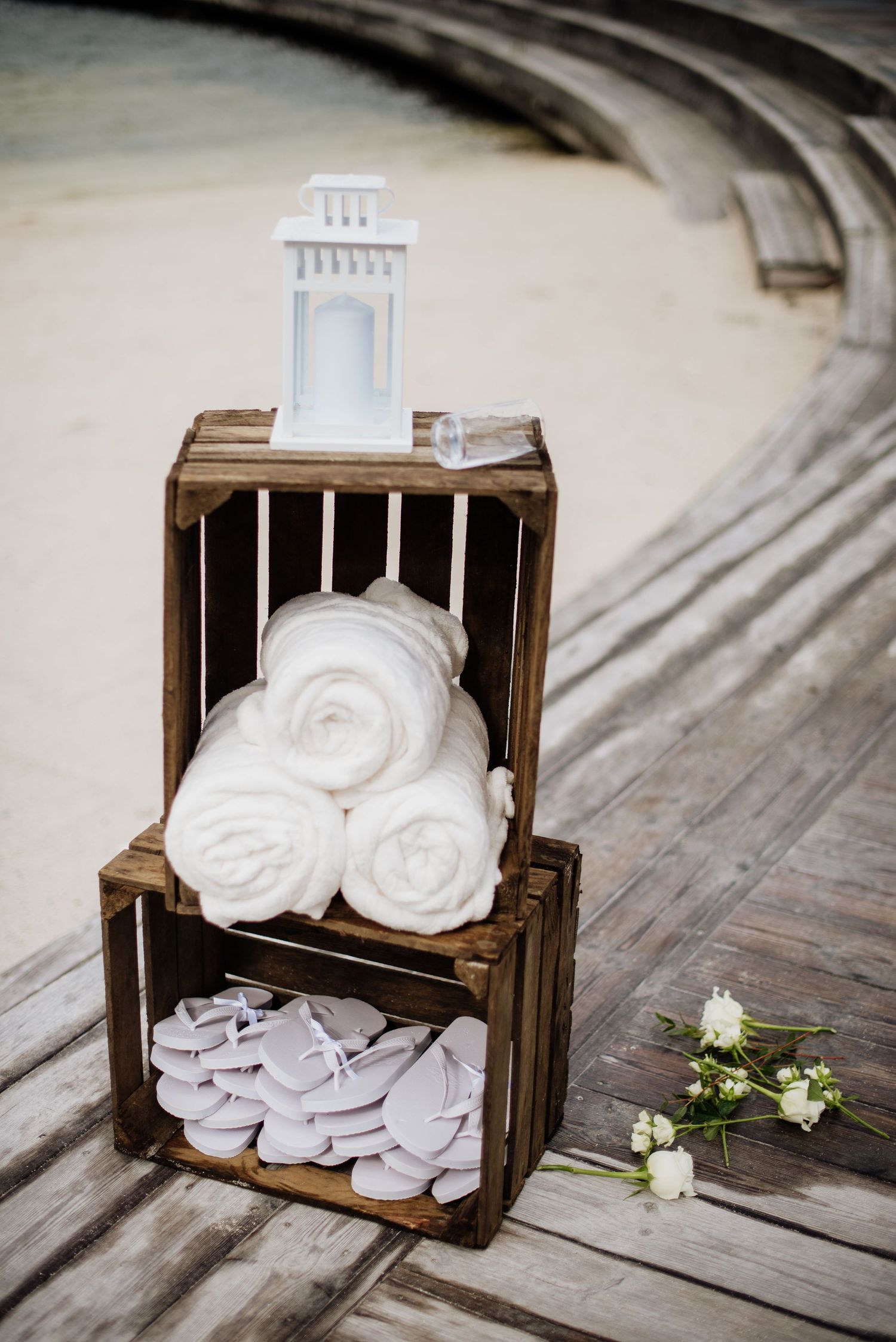 Rustic wooden crates display rolled white towels and spa amenities with a decorative lantern and floral accents at Villa Malla in Norway.