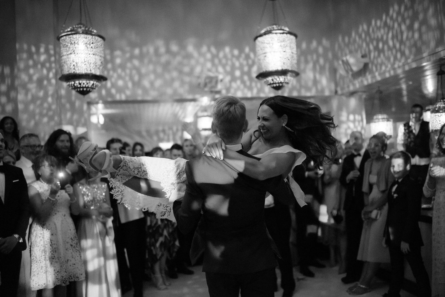 Couples dance together at an elegant black and white party under vintage lanterns with crowd watching.