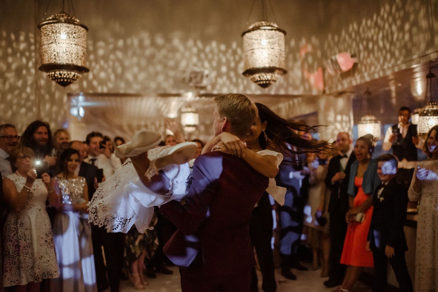 Guests dancing under decorative metal lanterns at an elegant indoor celebration with ambient lighting.