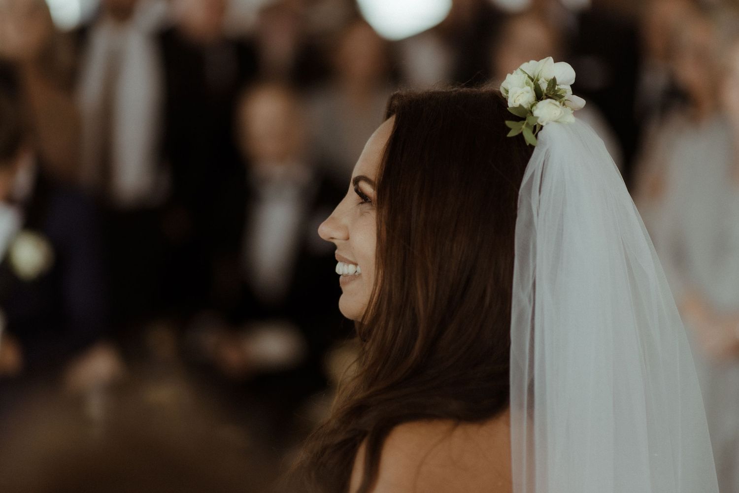 Joyful bride with a traditional white veil and floral crown laughs during wedding celebration at Villa Malla in Norway.
