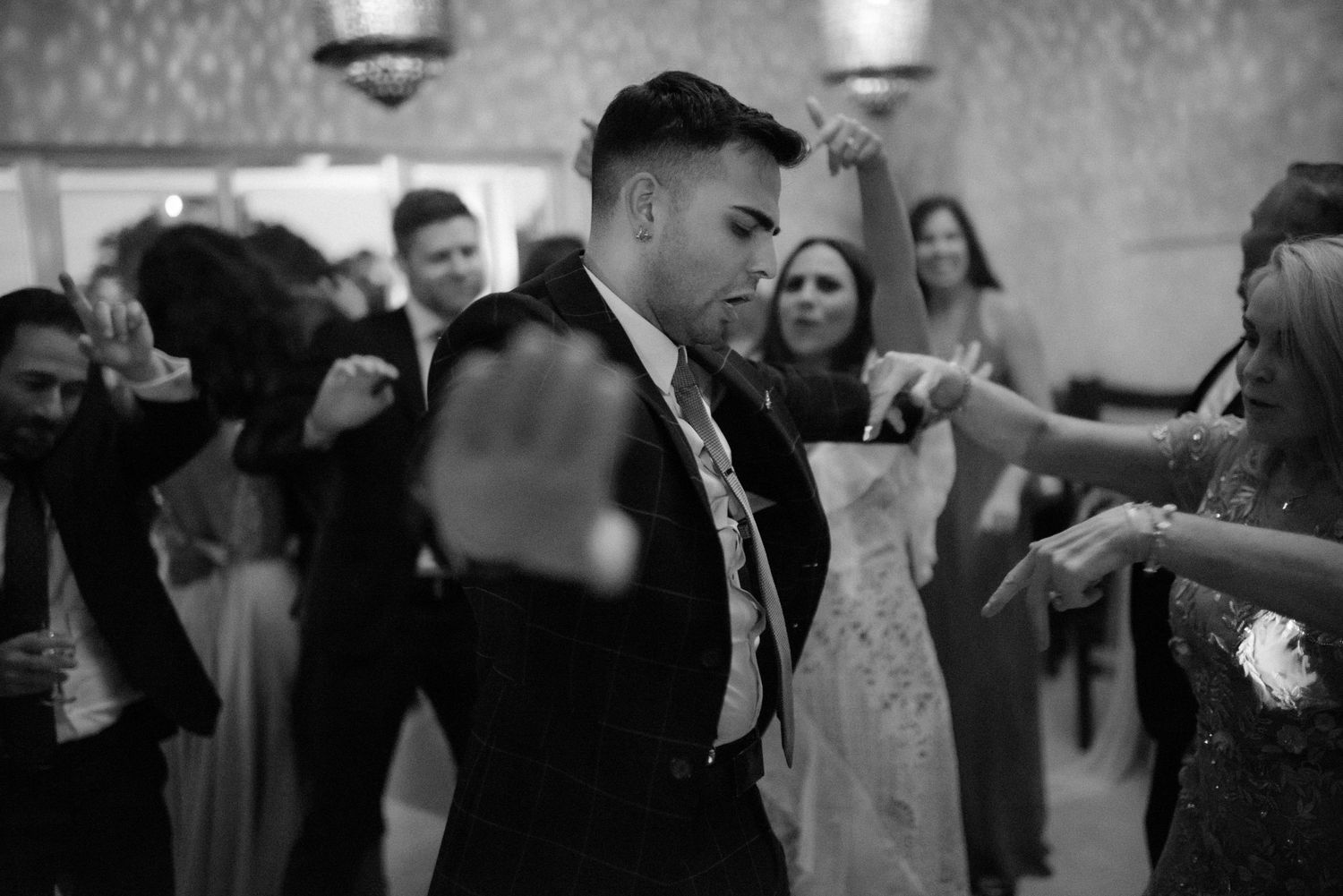 Wedding guests enjoying themselves on the dance floor at a reception in black and white photography.