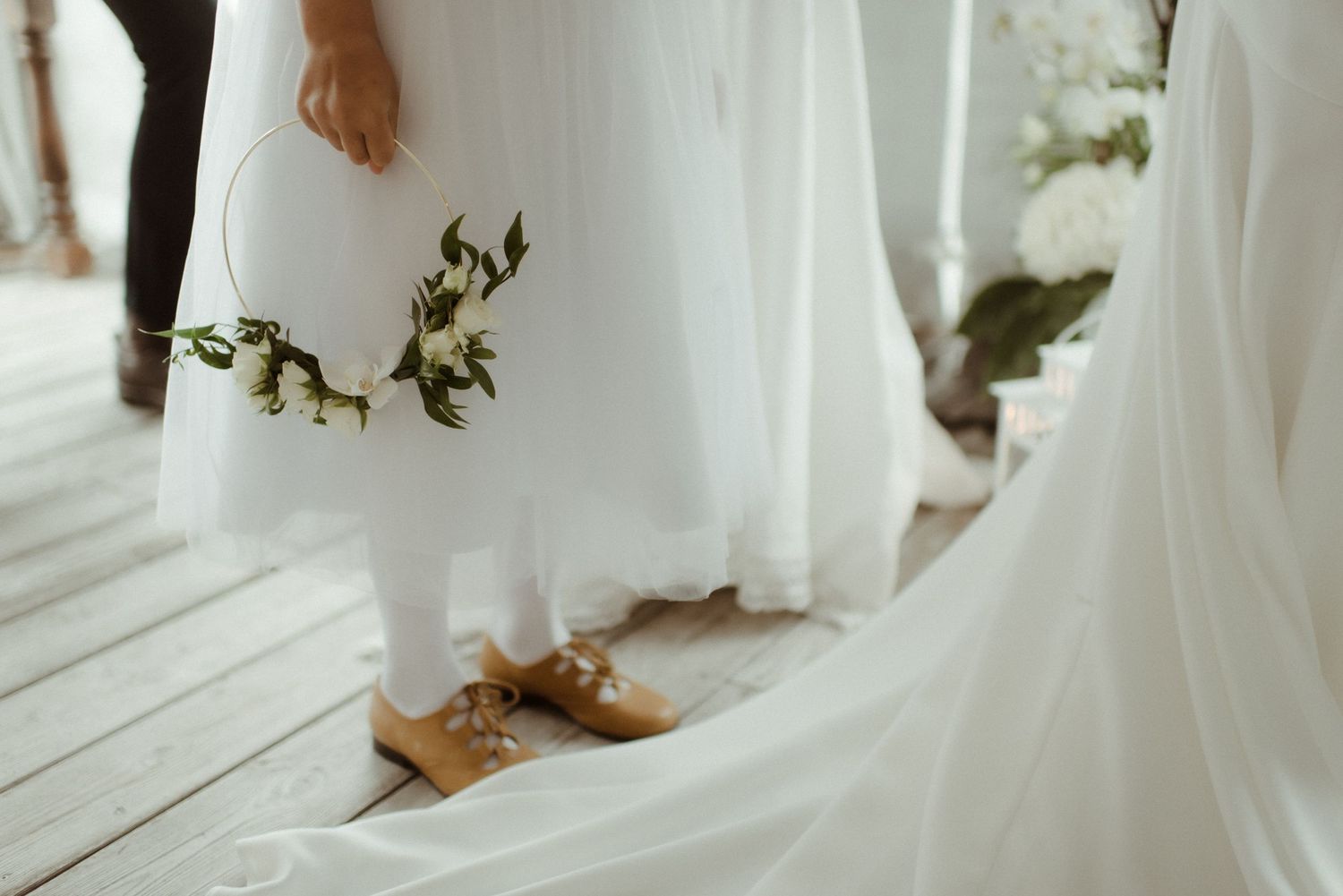 Close-up view of brown leather shoes and flowing white wedding dress hem against a light wooden floor at Villa Malla in Norway.