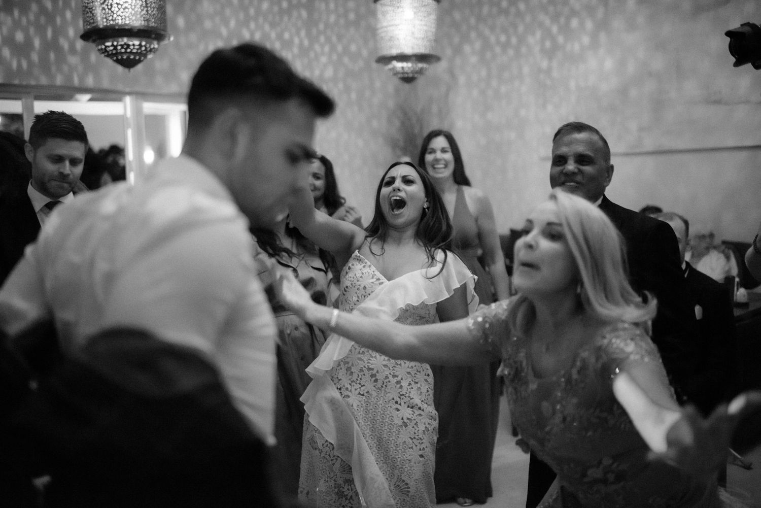 Wedding party dancing and celebrating in black and white during evening reception.