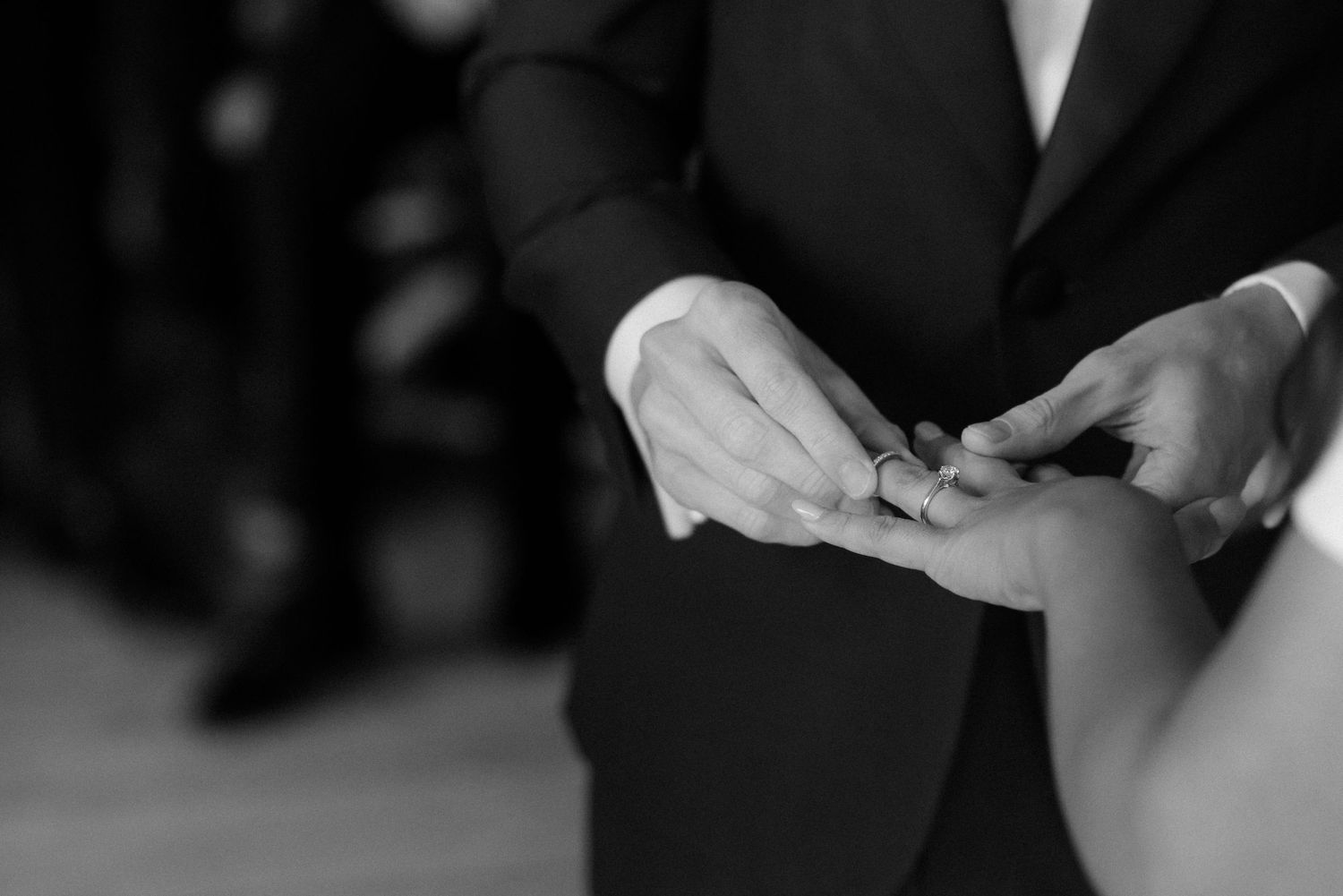Black and white close-up of hands exchanging wedding rings during a ceremony at Villa Malla in Norway.