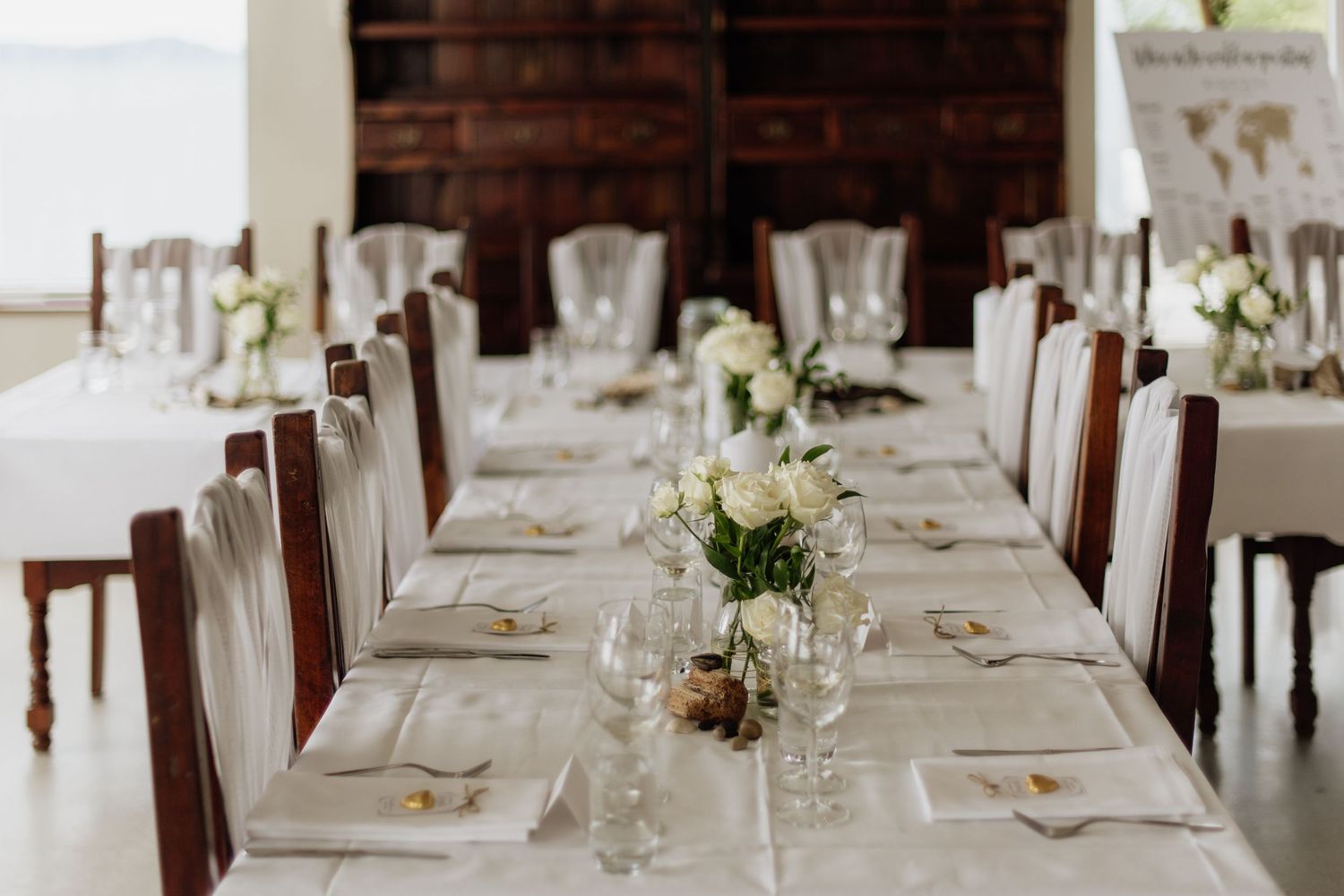 Elegant white dining table setup with floral centerpieces, crystal glassware and wooden chairs at a formal event at Villa Malla in Norway.