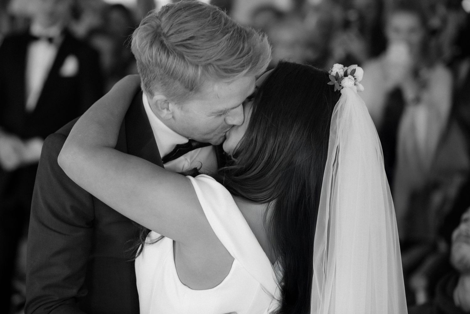 A black and white wedding photo shows an intimate moment between newlyweds sharing a kiss during their reception at Villa Malla in Norway.