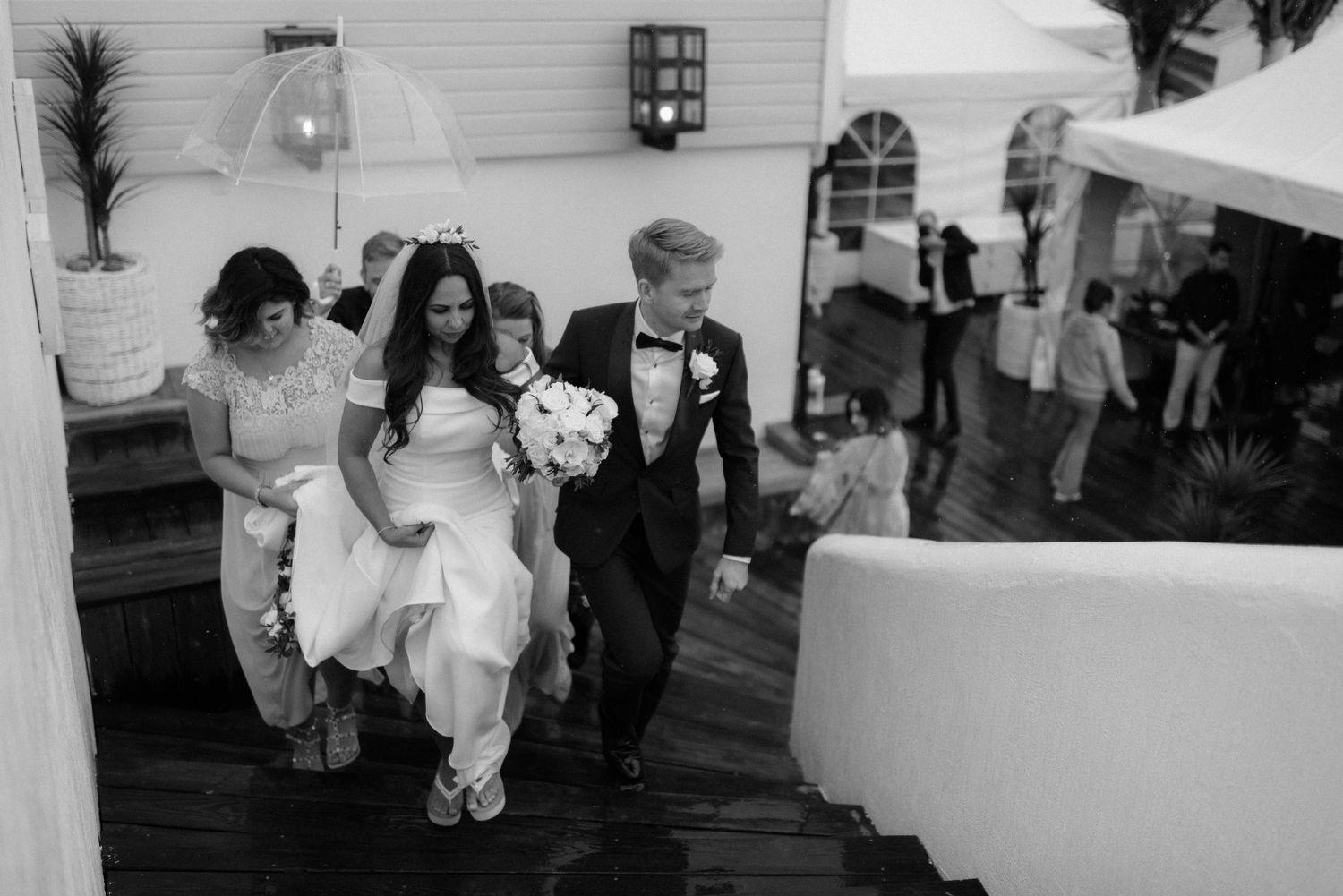 A wedding party descends wooden steps during a black and white outdoor celebration at Villa Malla in Norway.