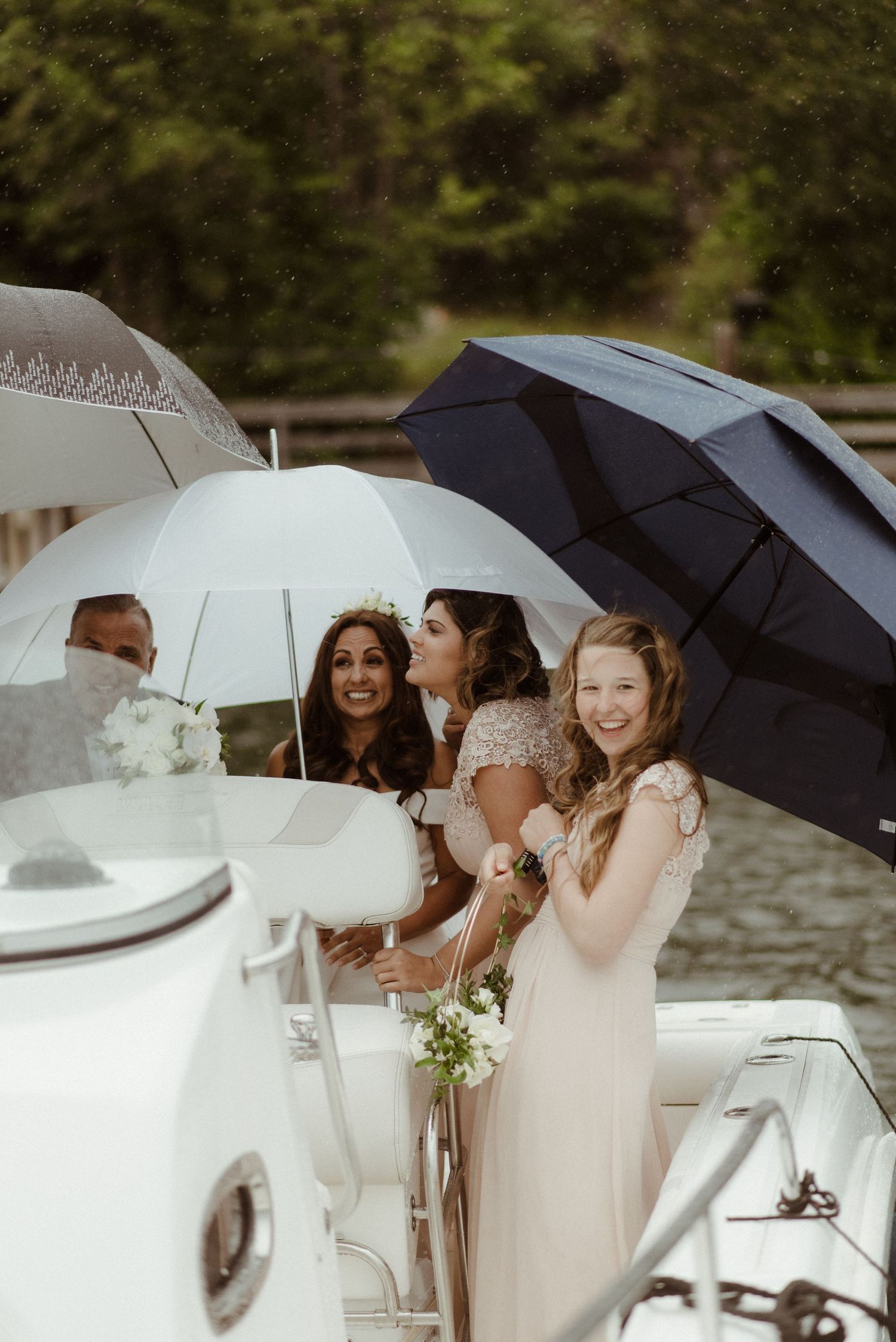 Wedding celebration on a boat with attendees holding white umbrellas and smiling during an overcast day at Villa Malla in Norway.