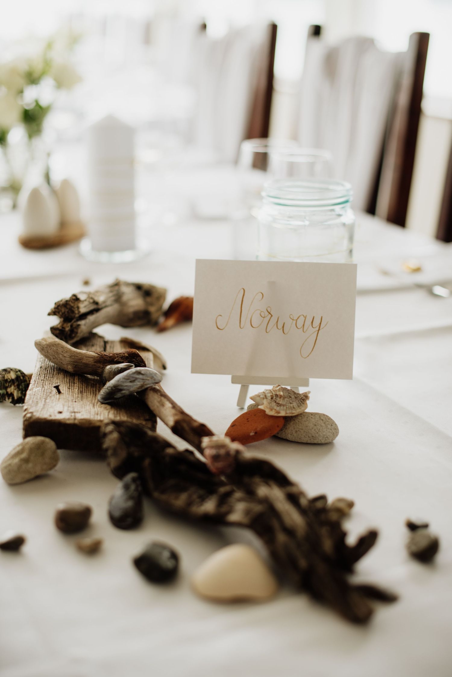 Rustic table setting with driftwood, stones, and glass jar centerpiece featuring a handwritten 'Norway' place card at Villa Malla in Norway.