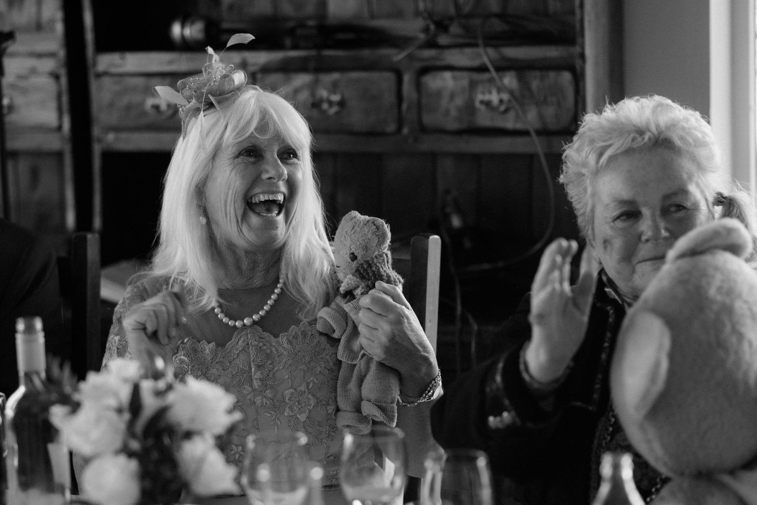 Black and white photo of a joyful celebration at an elegant dinner table with candlelight and laughter at Villa Malla in Filtvet, Norway.