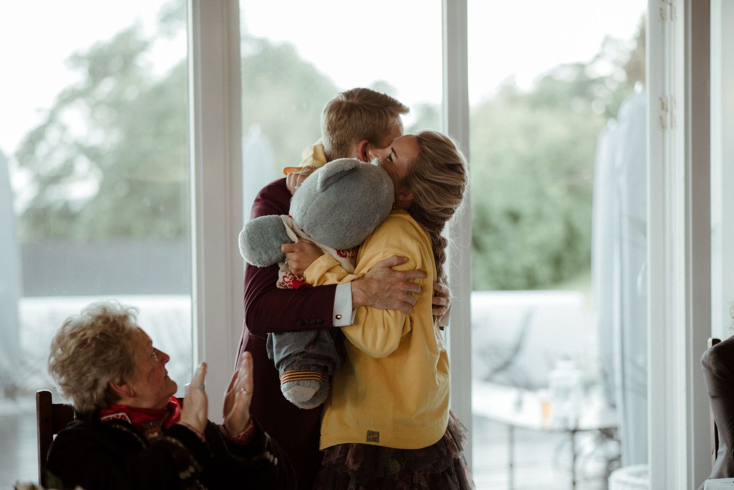A tender family moment by a bright window with warm embraces and gentle interactions at Villa Malla in Filtvet, Norway.