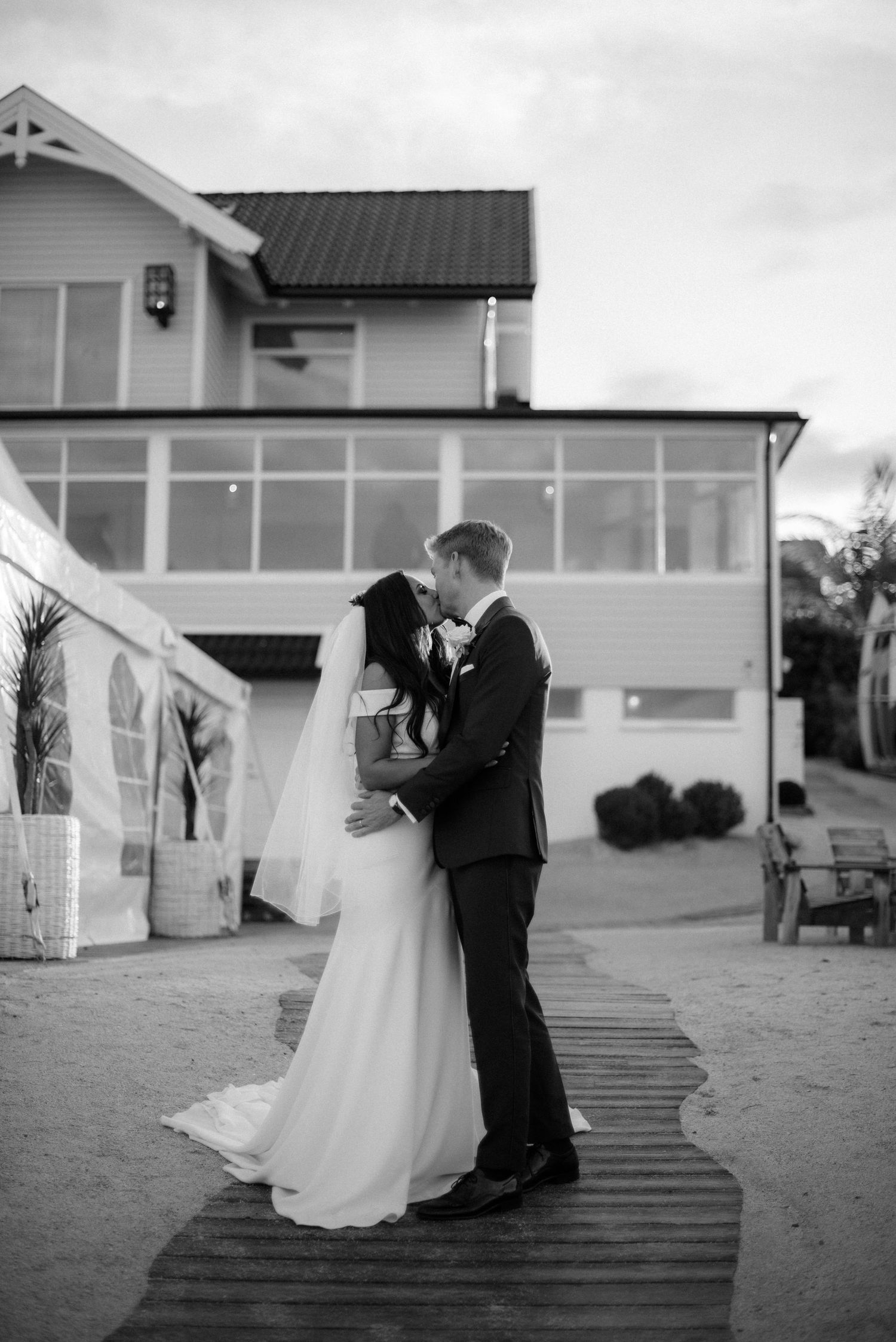 A romantic wedding couple shares an intimate moment on a wooden boardwalk outside a Villa Malla in Filtvet, Norway.