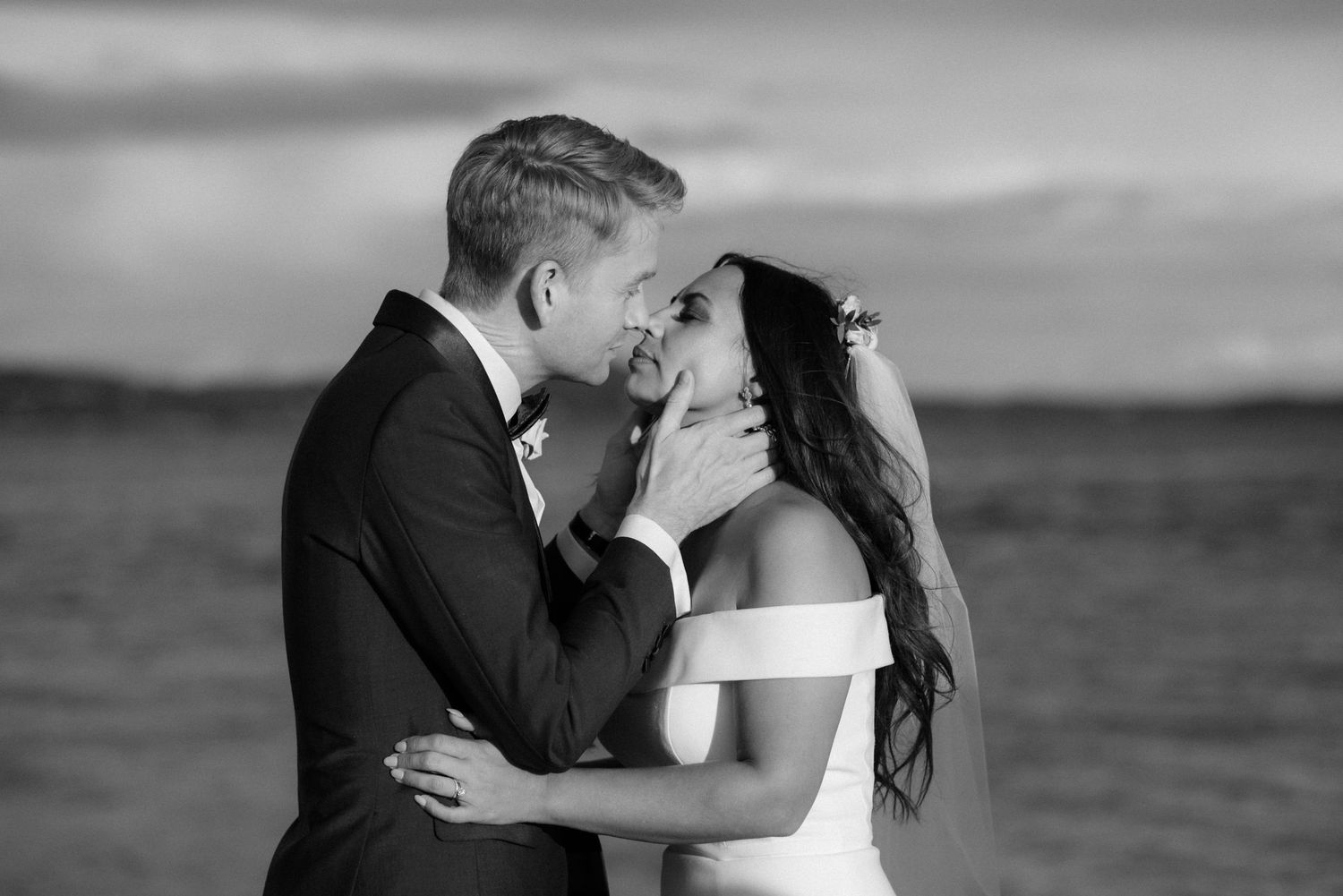 A romantic black and white wedding moment between newlyweds embracing against a dramatic fjord backdrop at Villa Malla in Filtvet, Norway.