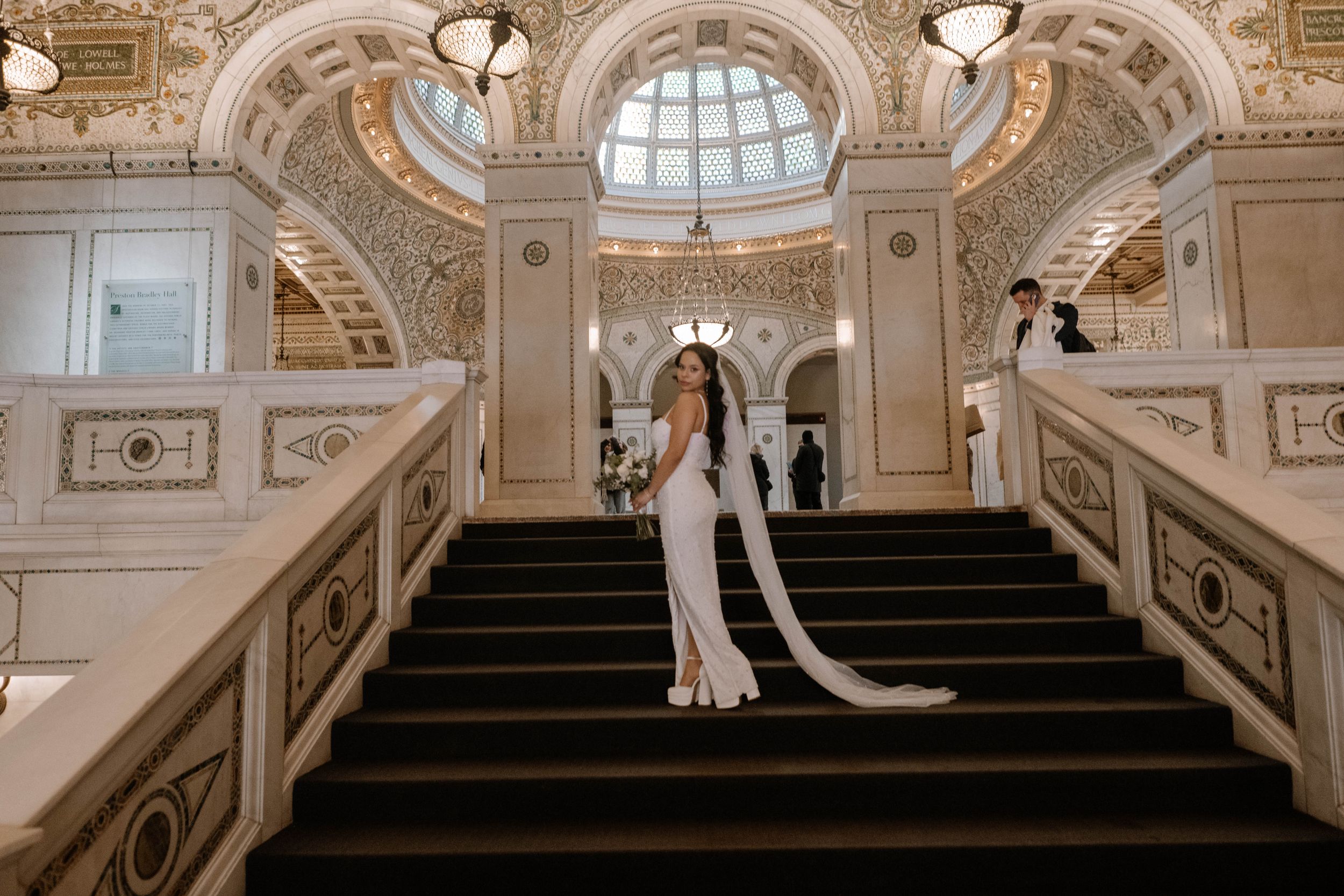 Formal gathering on an ornate marble staircase inside a grand historic building with elegant architectural details.