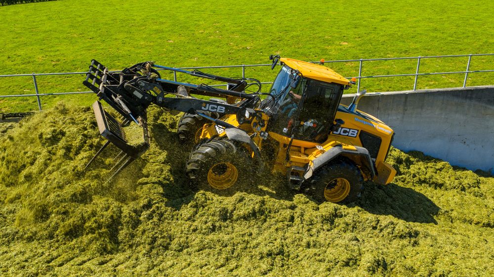 Yellow and black construction equipment displayed in a row on bright green grass at an outdoor equipment show.