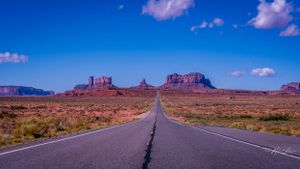 Long desert highway leads to Monument Valley's iconic buttes and mesas.