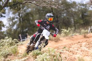 Motocross rider navigating rough terrain on dirt bike with protective gear.