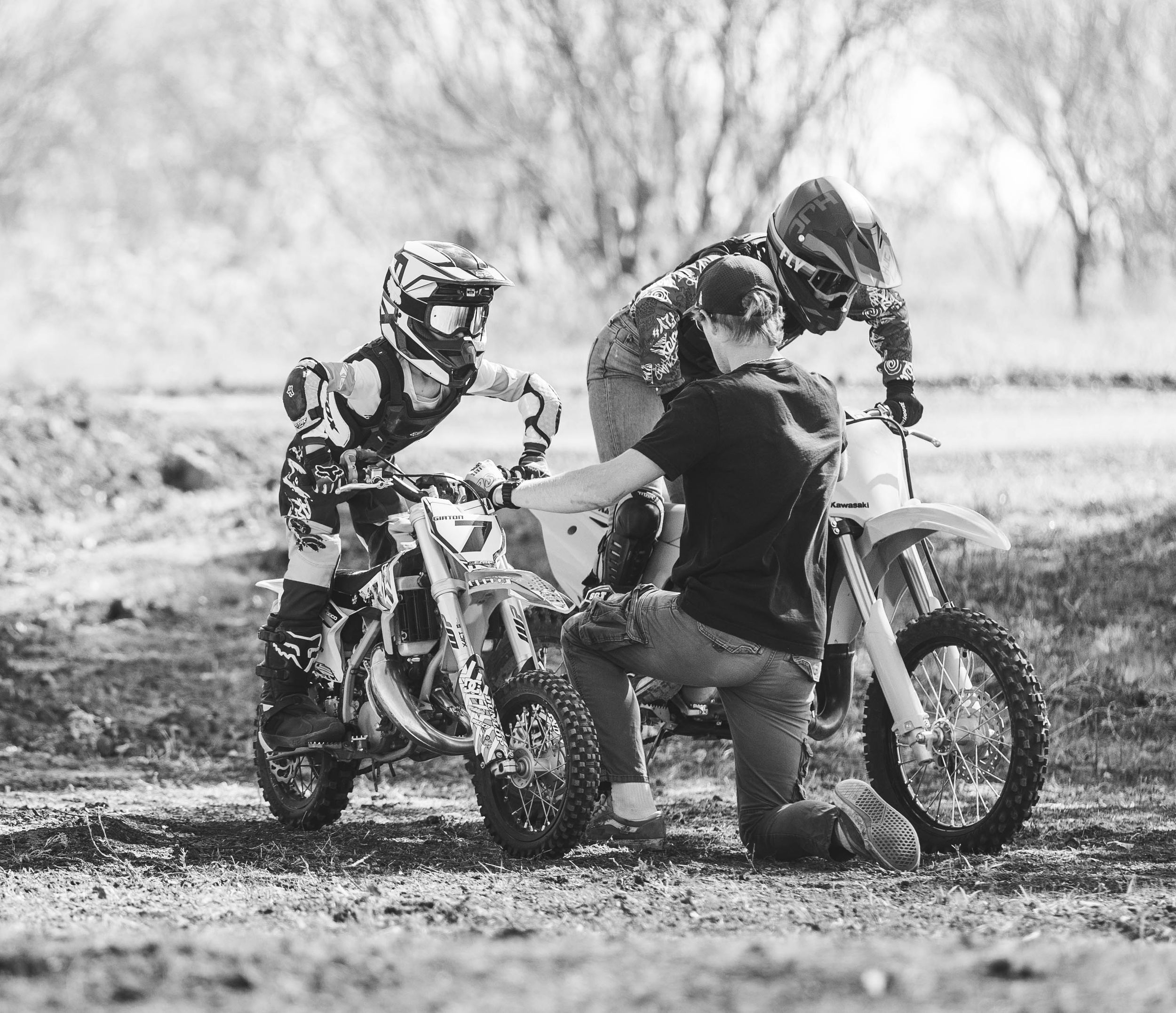 Black and white image of dirt bike training session with two motorcycles on muddy terrain.