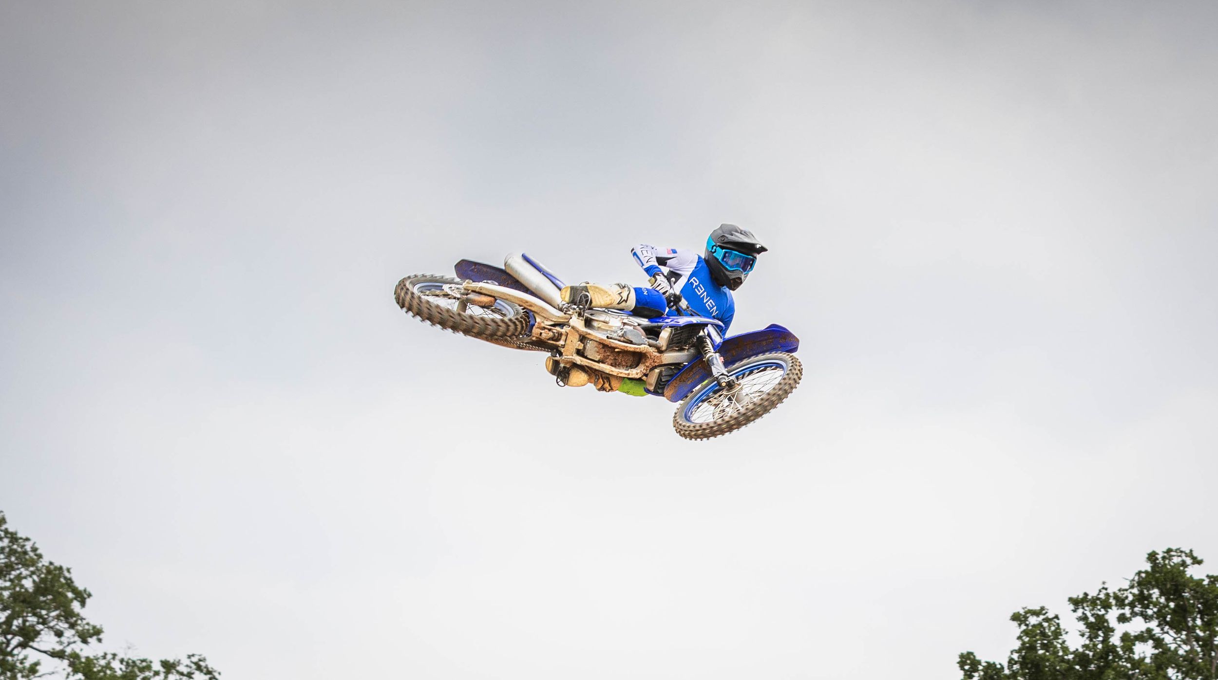 Dirt bike rider performs sideways whip maneuver during dramatic aerial stunt.