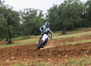Dirt bike rider navigating through red clay track during off-road competition.