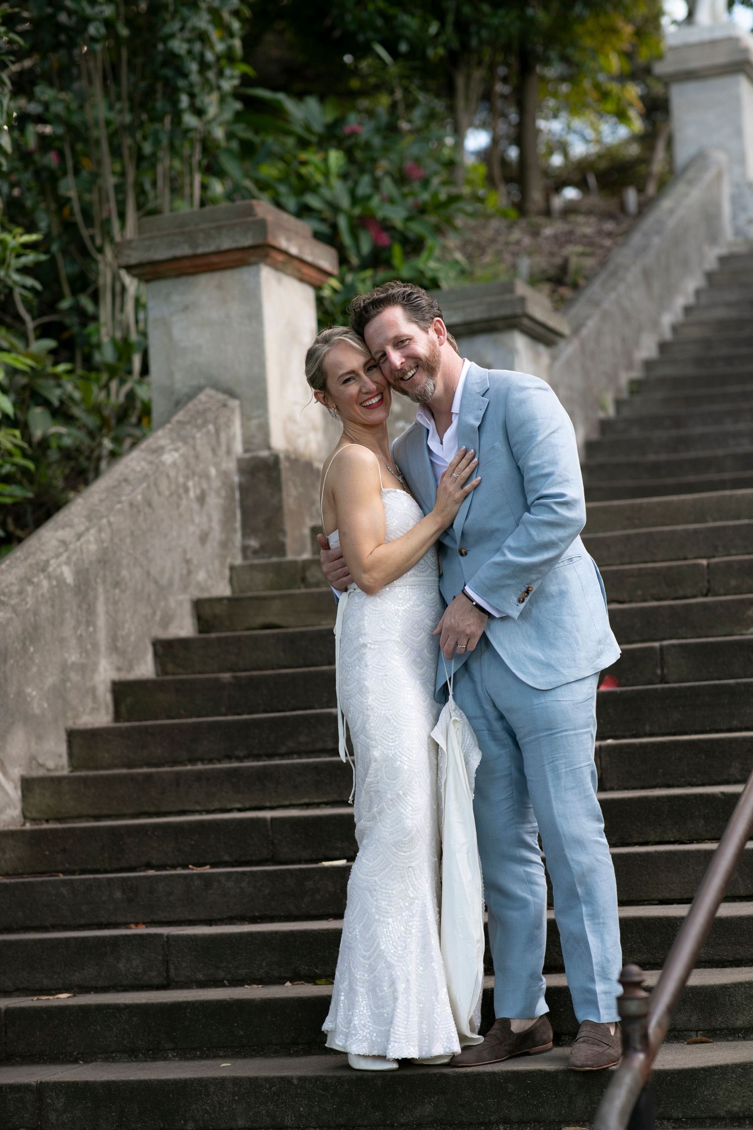A couple sharing a joyful moment on historic stone steps during their wedding day.