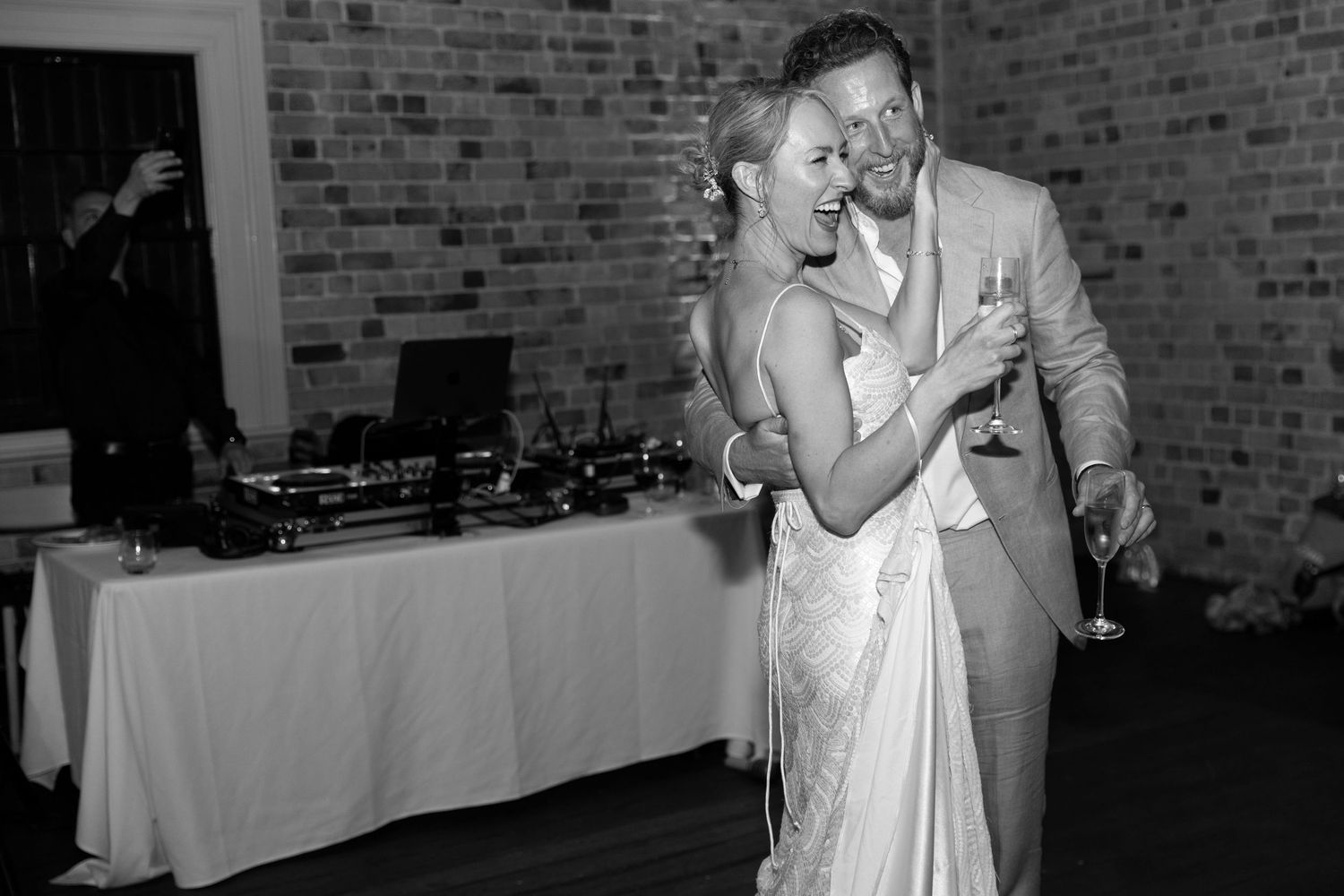 A black and white photo of a wedding couple dancing together at their reception.