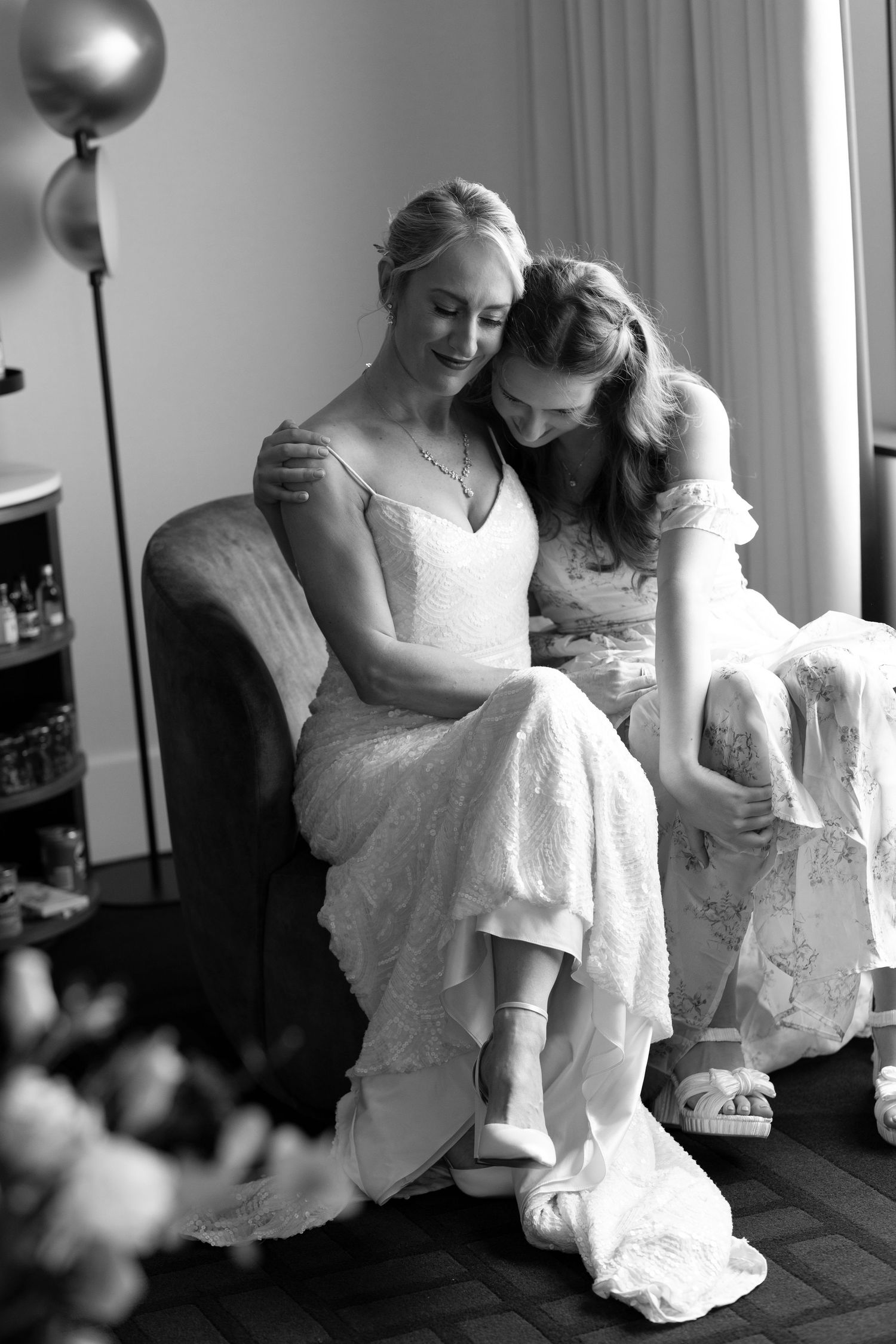 A tender black and white moment captured in a room with soft window light.