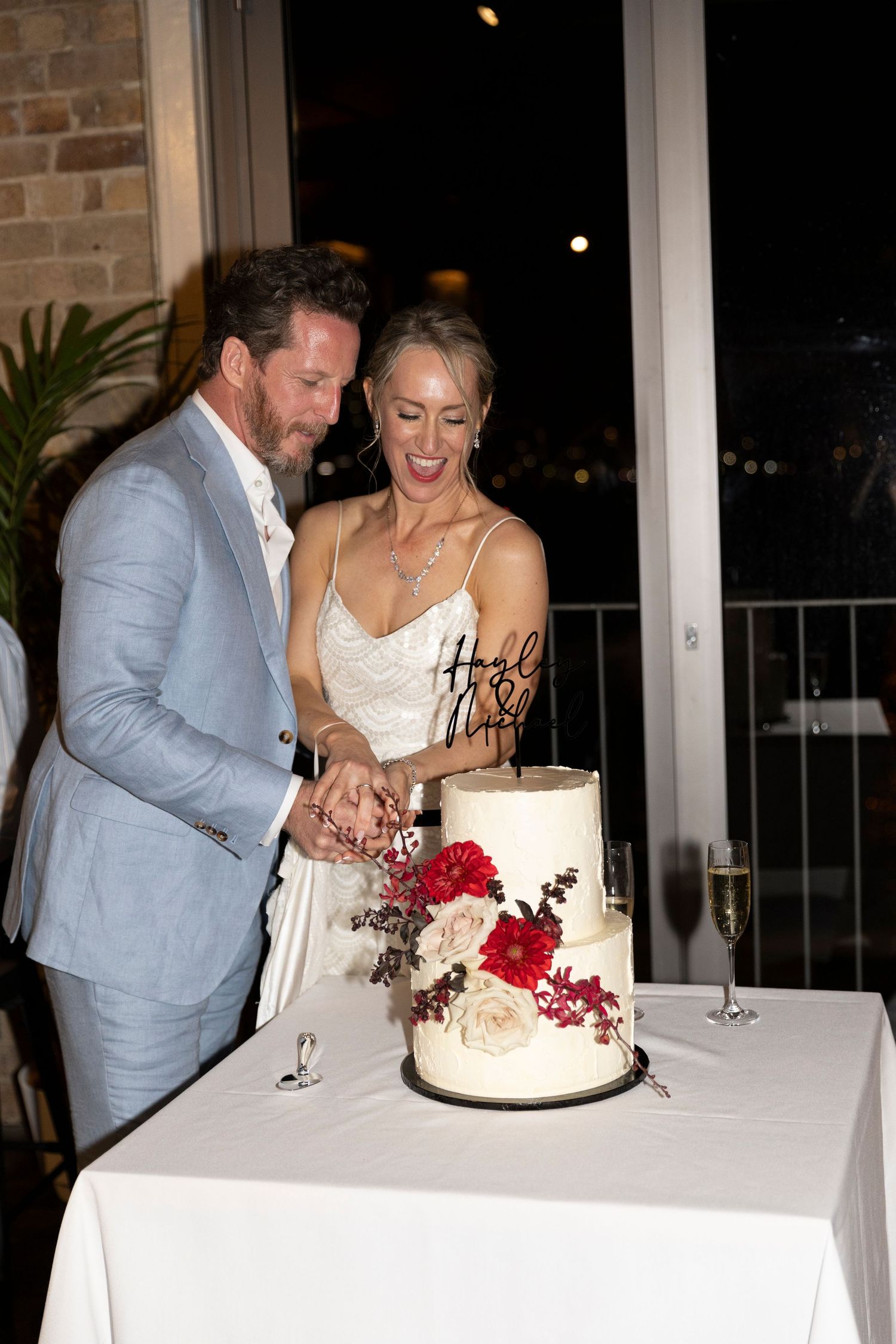 Couple cuts elegant white and red wedding cake together at reception.