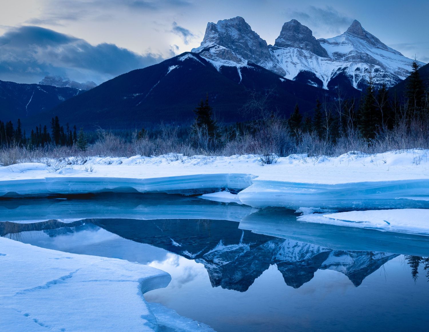 Three Sisters Mountains in Canmore, Alberta, Canada, blue hour, ice on a freezing winter morning