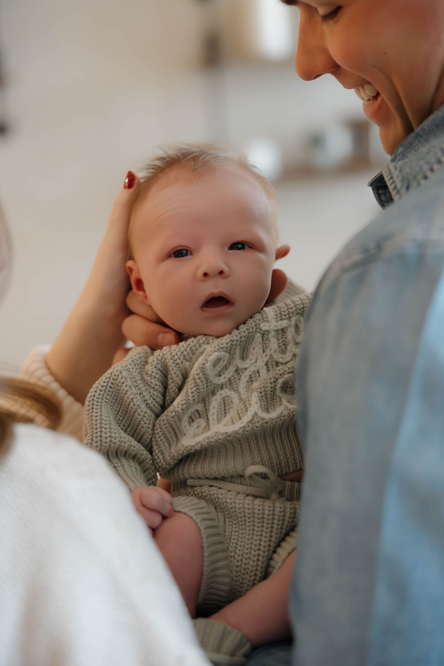 A baby in a gray knit sweater shares tender moments with a caregiver in a series of intimate close-up shots.