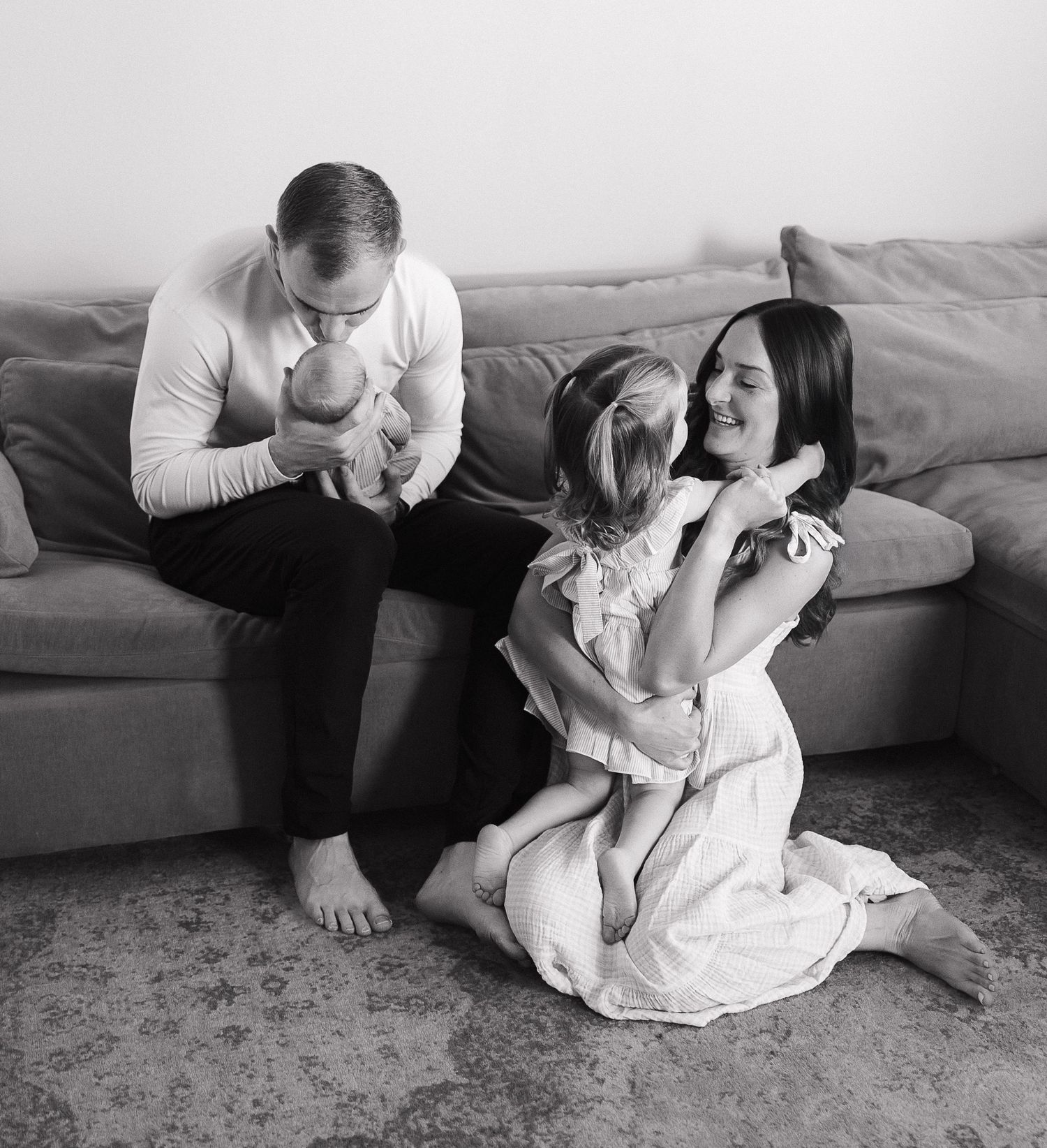 Black and white photos show tender moments between parent and child sitting on floor near sofa.