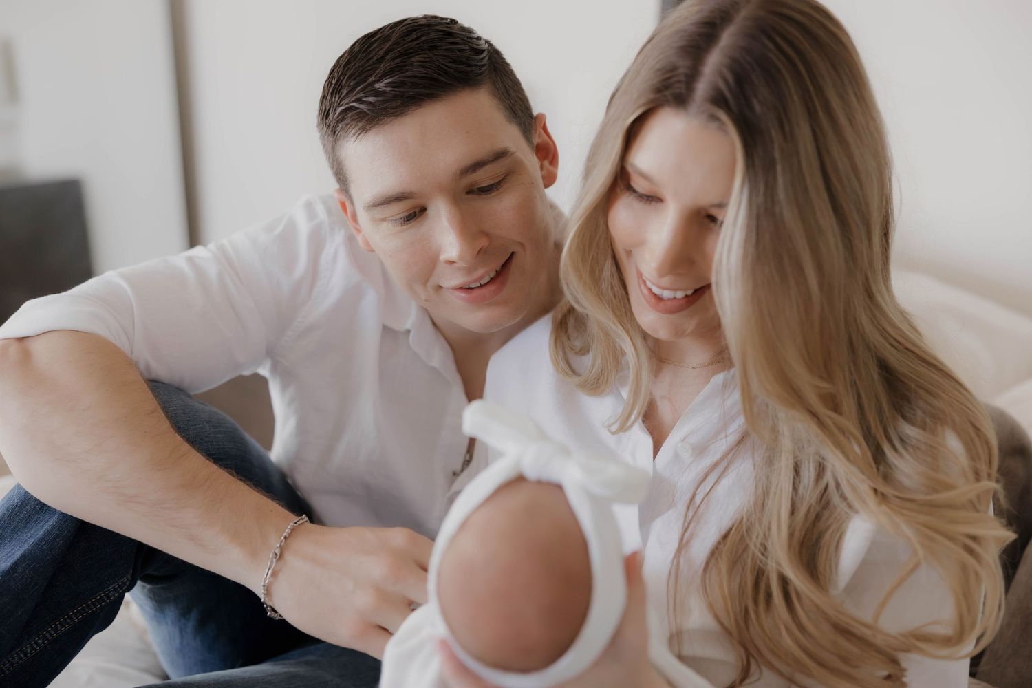 A couple shares tender moments together while relaxing at home in casual white attire.