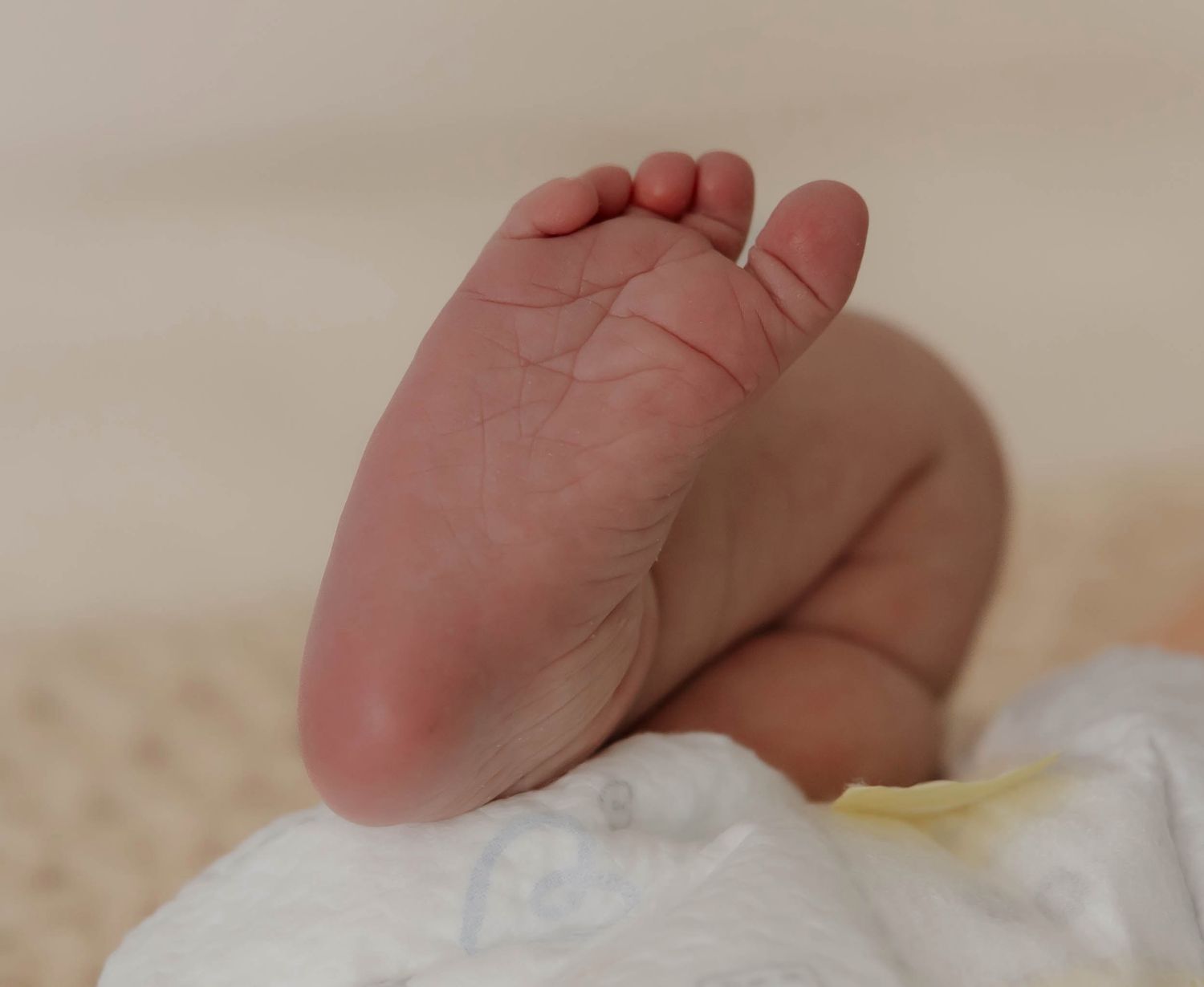 A close-up series of images showing a baby's tiny feet and toes against a soft white background.