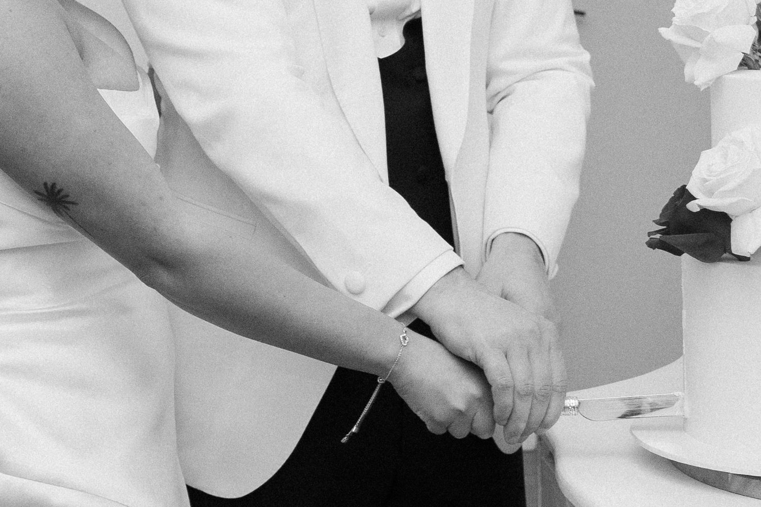 Close-up of hands clasped together in a white suit jacket at a formal event.