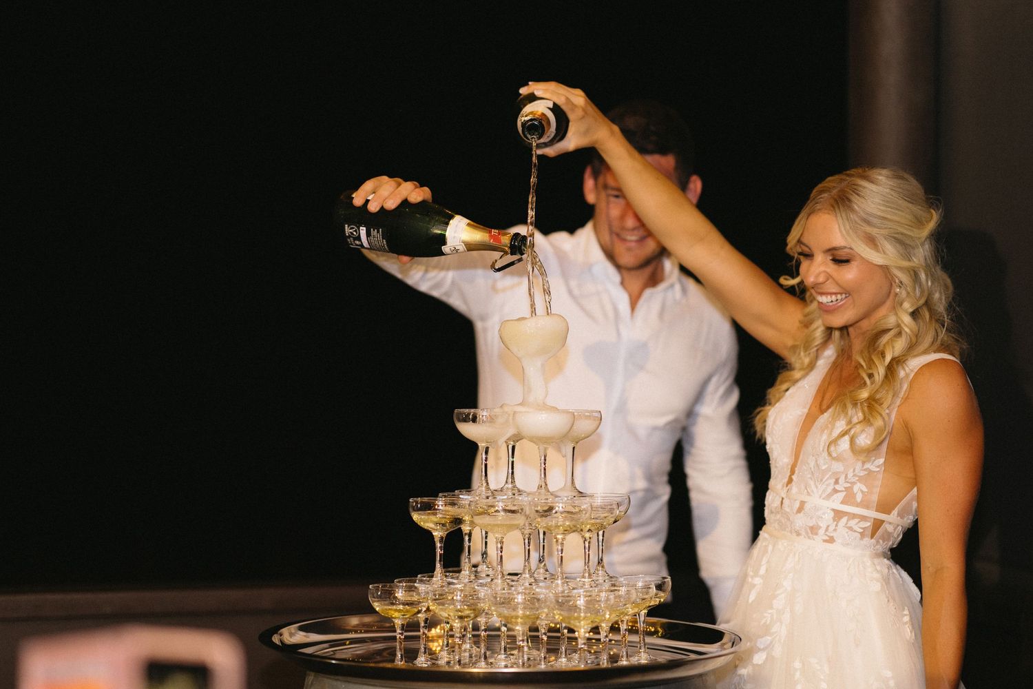Champagne tower being filled at elegant wedding reception.