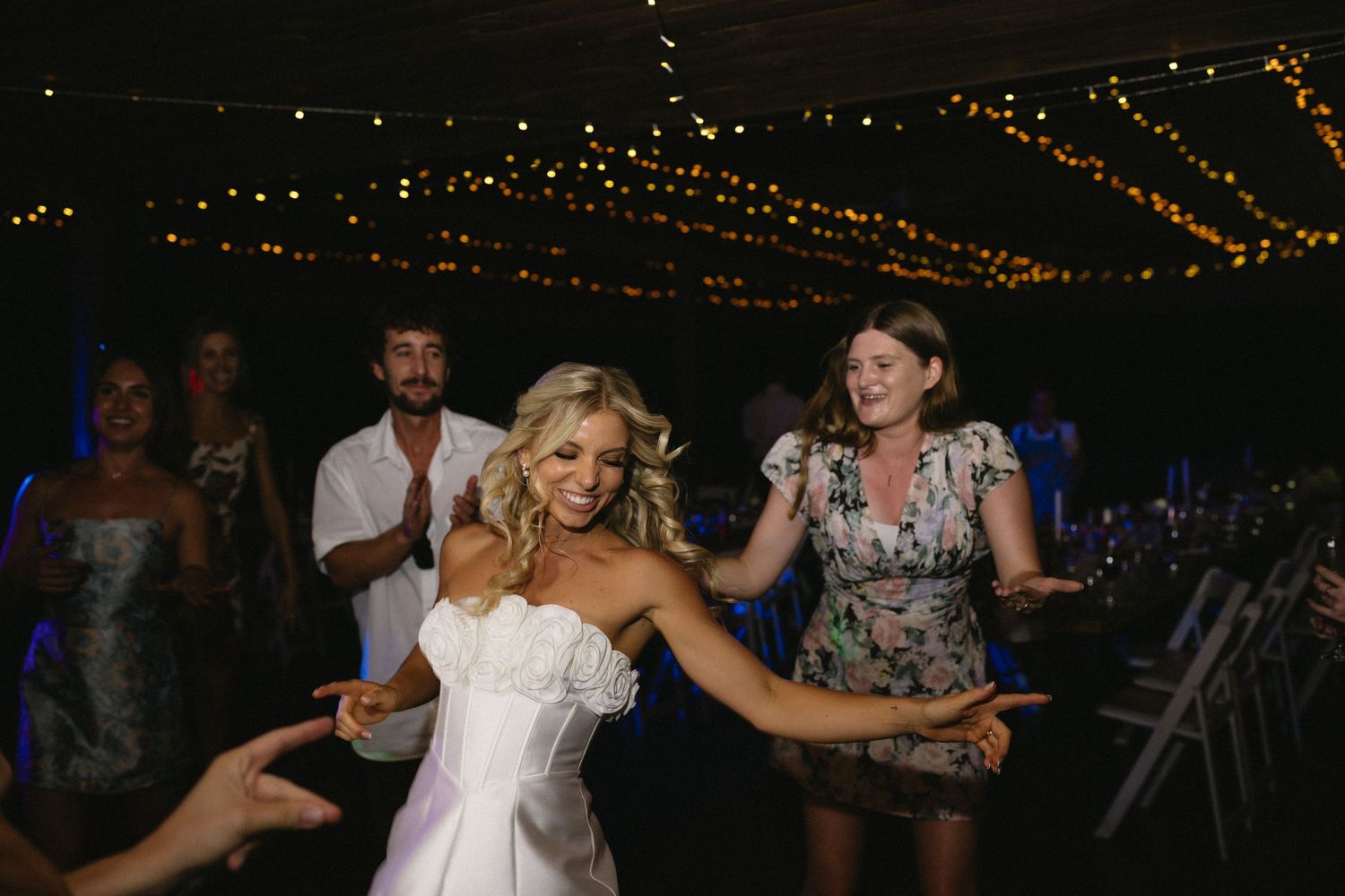 Wedding celebration on dance floor with string lights overhead.