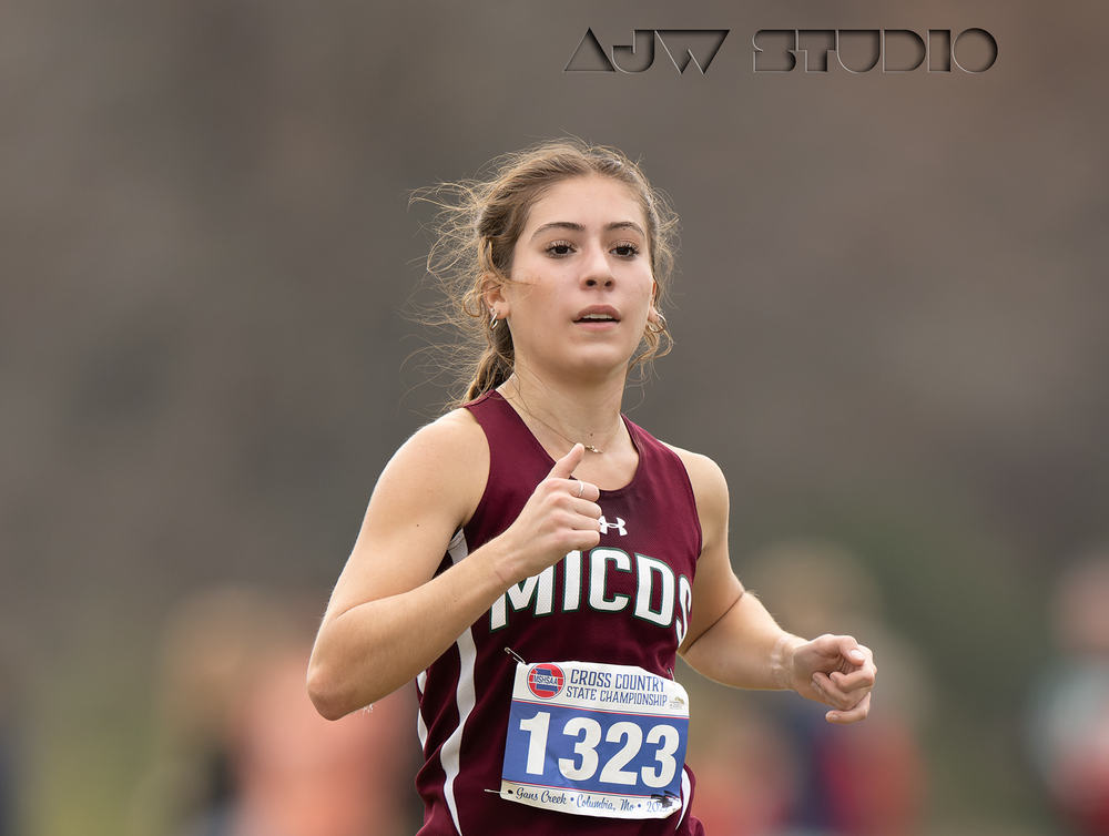 Track athlete in maroon uniform competes in outdoor running event.
