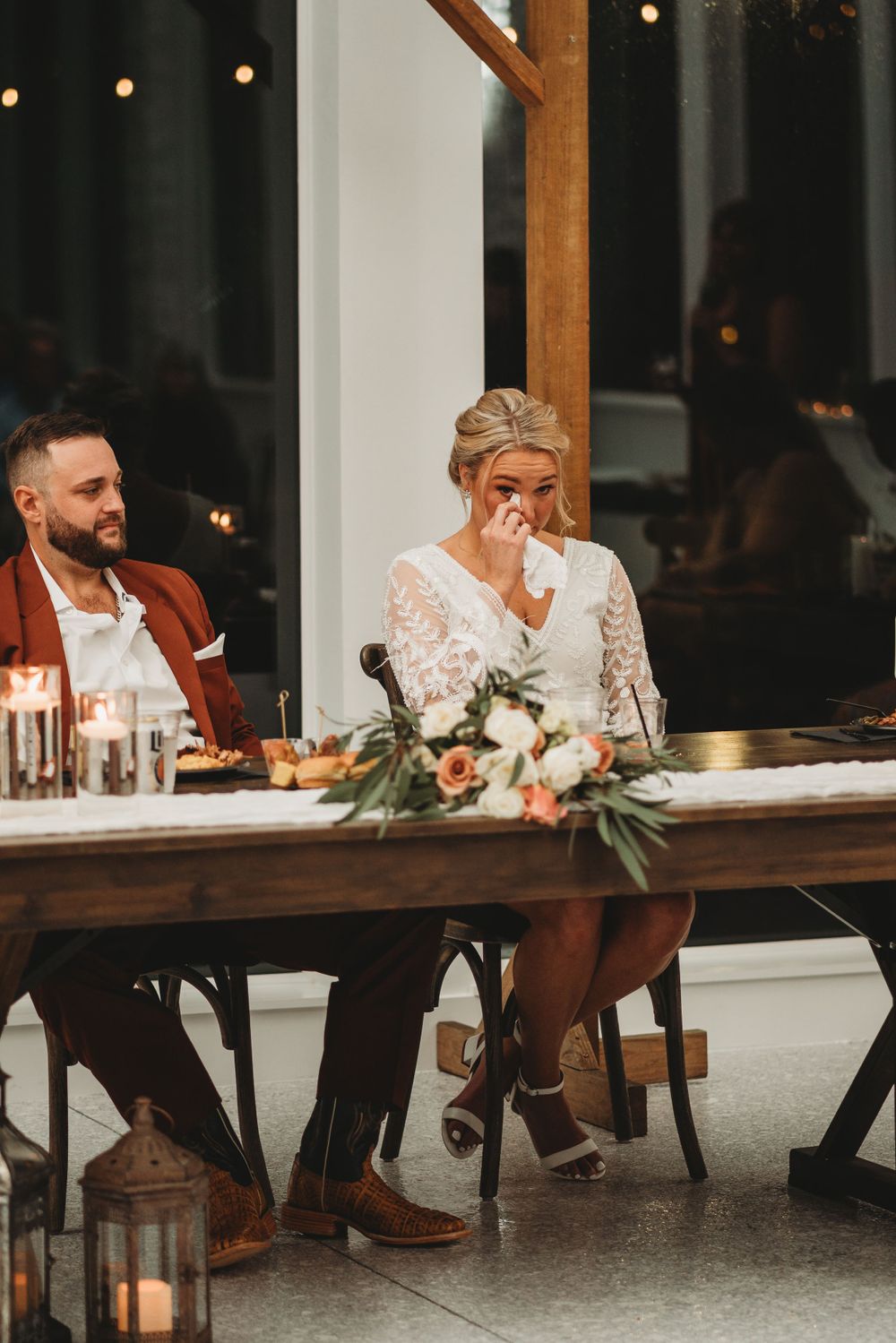 Emotional wedding reception moment captured at a candlelit head table.