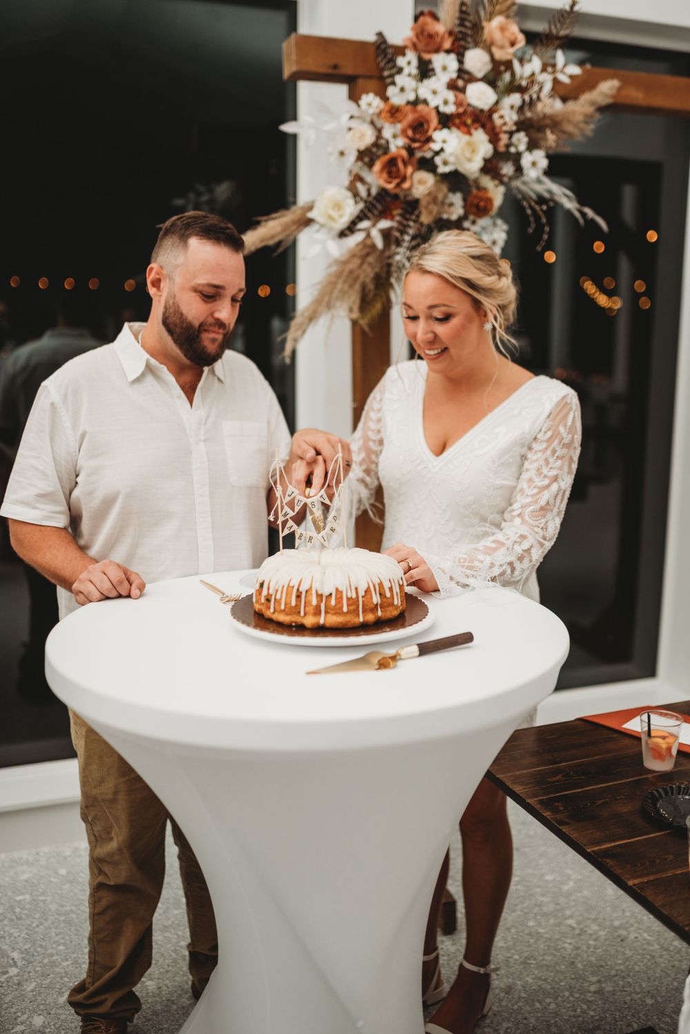 Newlyweds prepare to serve their bundt cake at an elegantly decorated reception.
