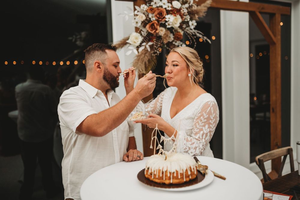 Playful cake feeding moment between newlyweds at their wedding reception.