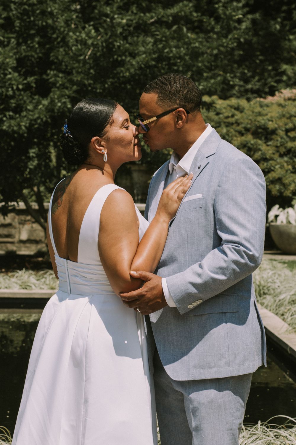 A bride and groom sharing a romantic moment outdoors, leaning in for a kiss, showcasing wedding photography by Empax Studios.