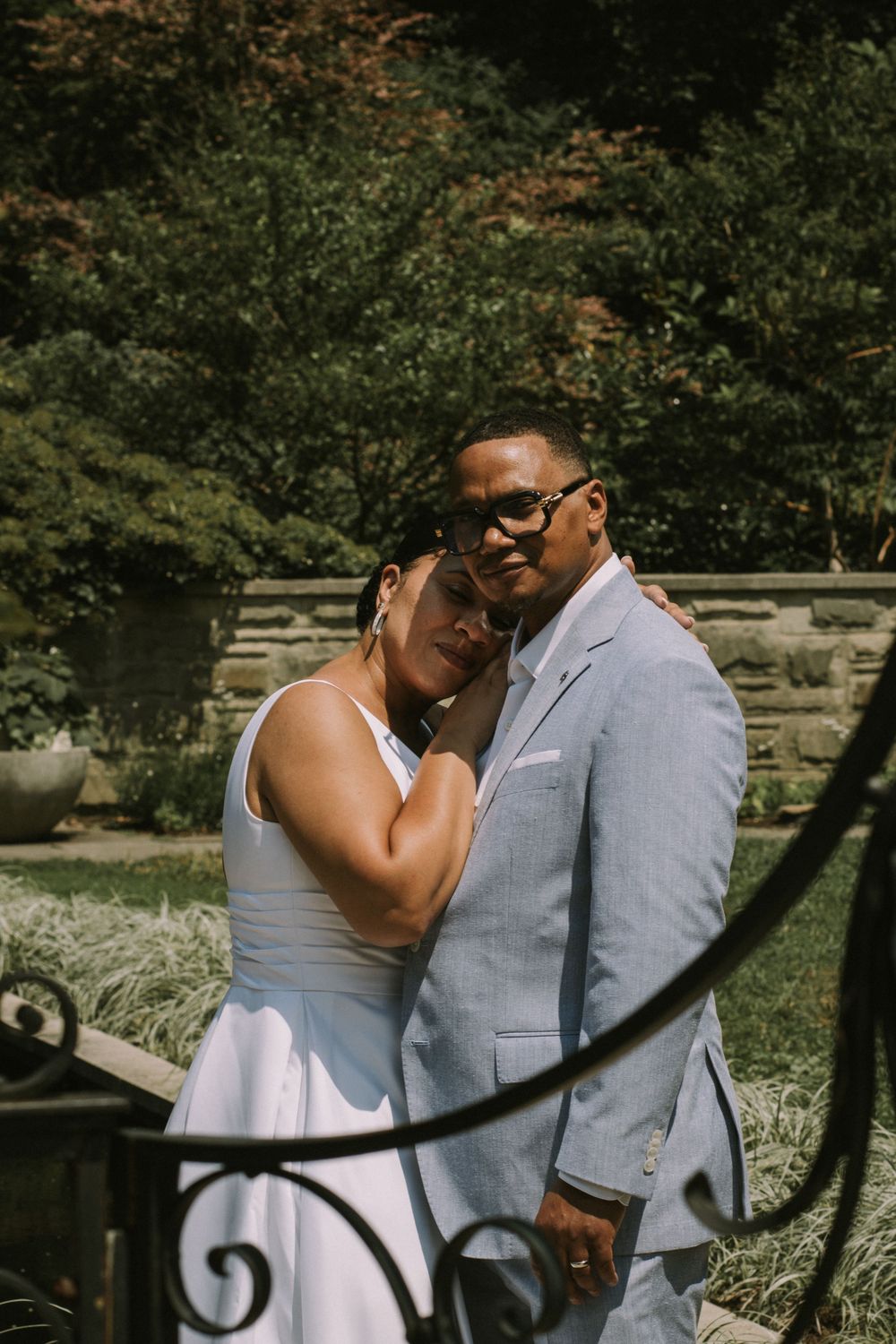 A bride resting her head on the groom's shoulder as they pose outdoors, showcasing intimate wedding photography by Empax Studios.