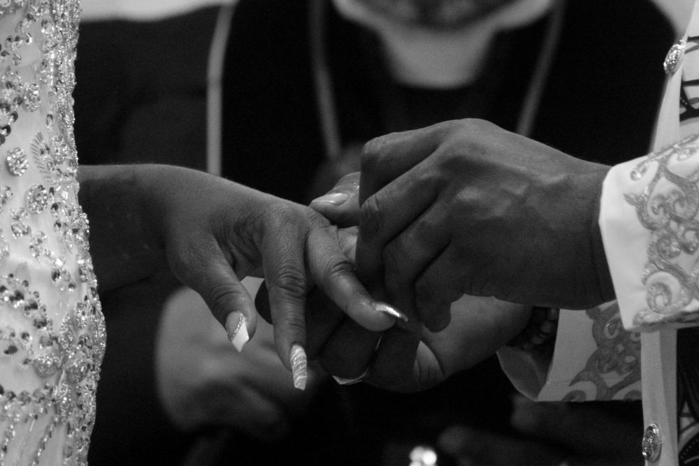 A black-and-white close-up of a bride and groom exchanging rings during their wedding ceremony, showcasing intimate wedding photography.