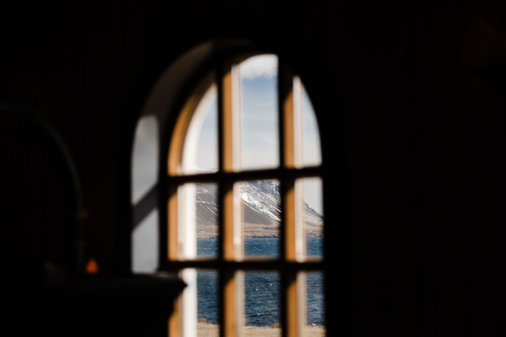 Sunlight streams through arched window creating geometric shadows.