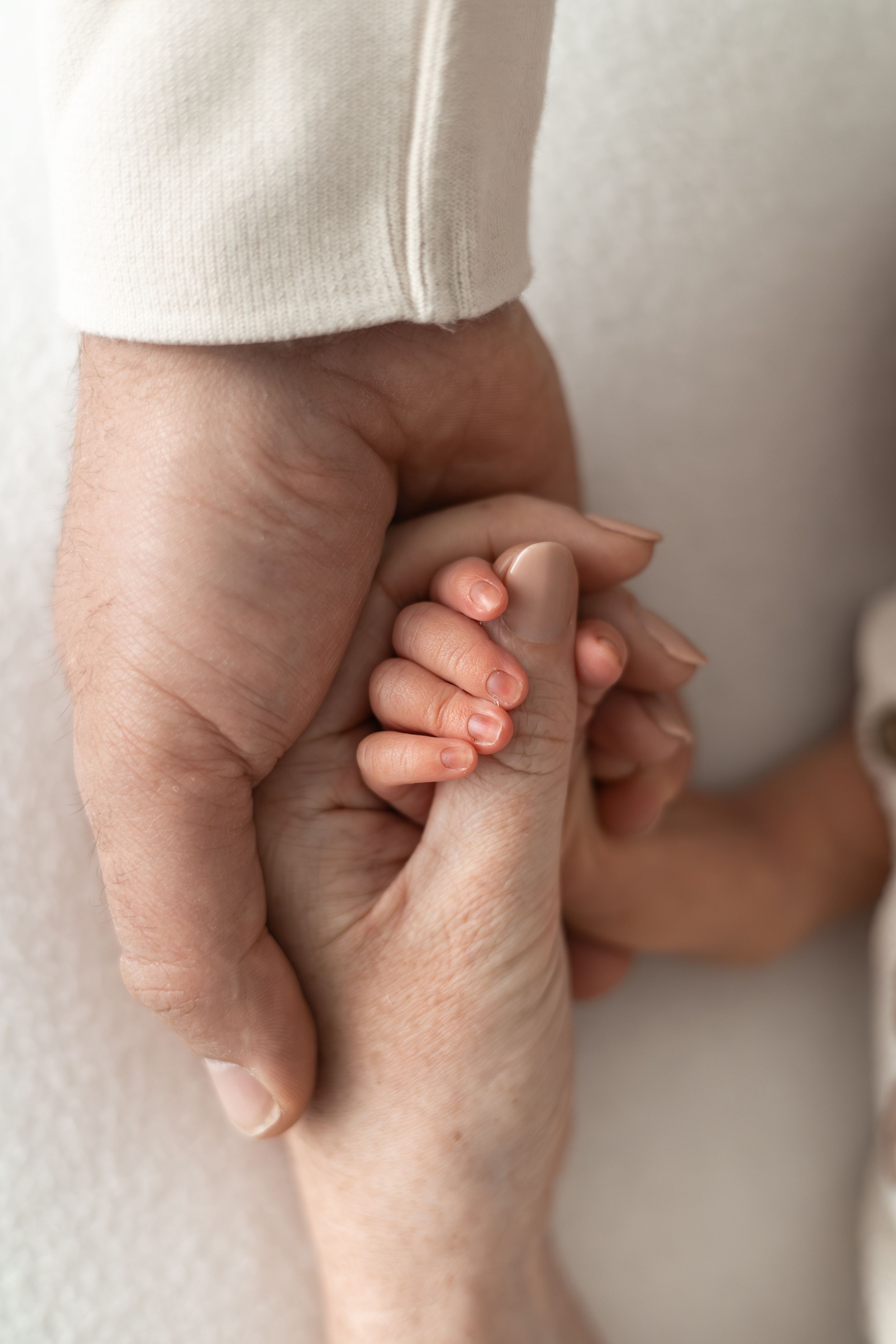 A newborn baby's tiny hand gently gripping an mam and dads fingers, showing love and new parenthood Nottingham newborn photographer