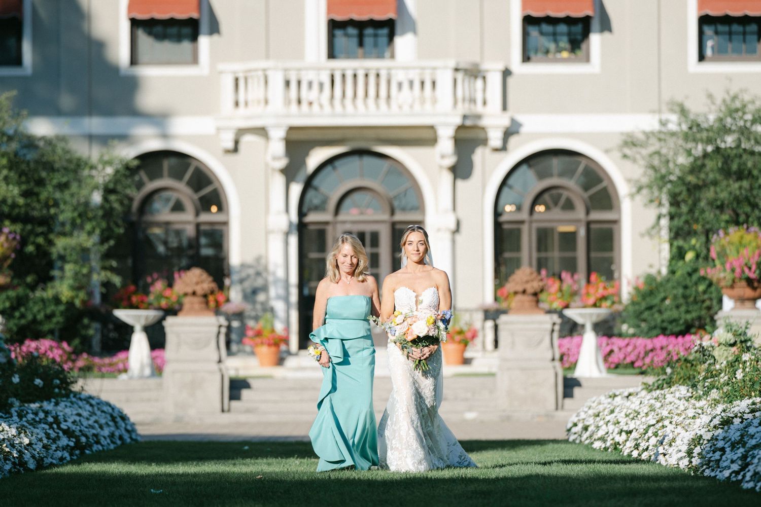 Armour House Wedding - Couple exchanges vows at outdoor wedding ceremony with lush floral arrangements and fountain backdrop.