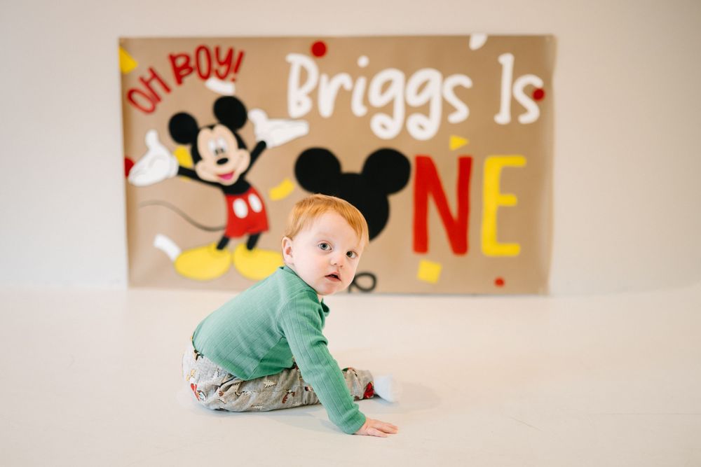First birthday photos in Brookings, SD with ONE letters and Mickey Mouse decorations.